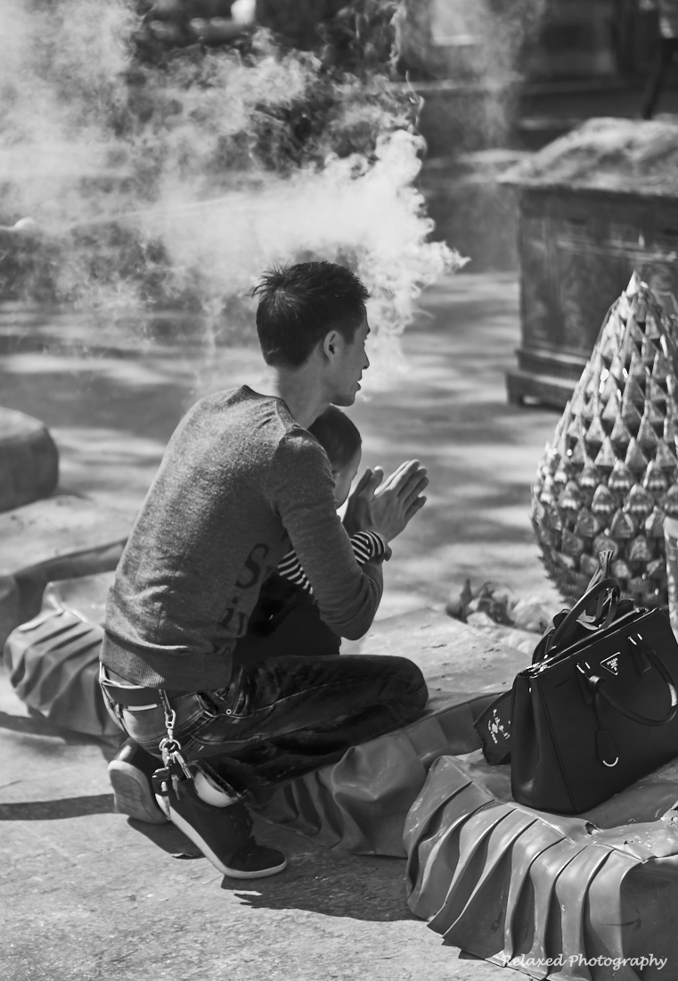So many thoughts and emotion come to mind when I look at this image. It depicts a father teaching his son how to pray to the Bhudda. The handbag shows that mum is with them, but maybe she stepped aside quietly to allow them this moment together. I’d