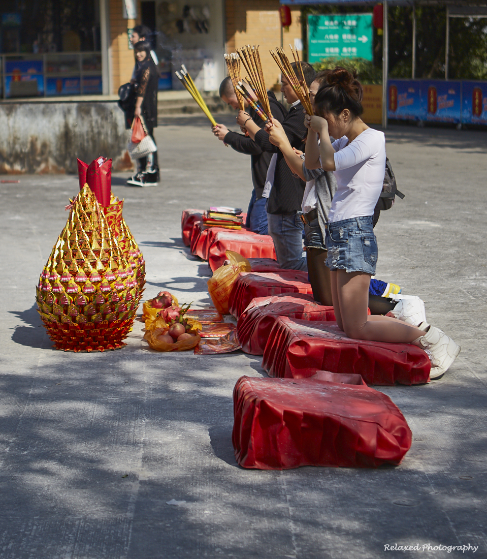 Shown here are people praying in front of the Bhudda statue and in front of them are some typical paper symbols brought to burn in the fire pits located around the statue.
