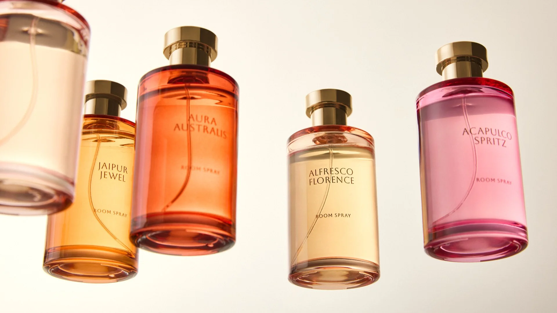 Five colorful perfume bottles with gold caps and labels, arranged against a light background.