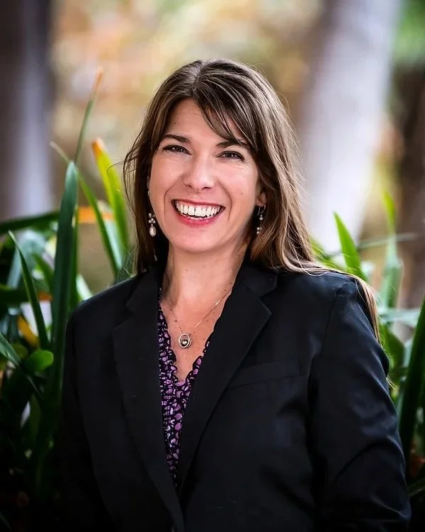 Picture of Davida Price in a purple and black top and black jacket.