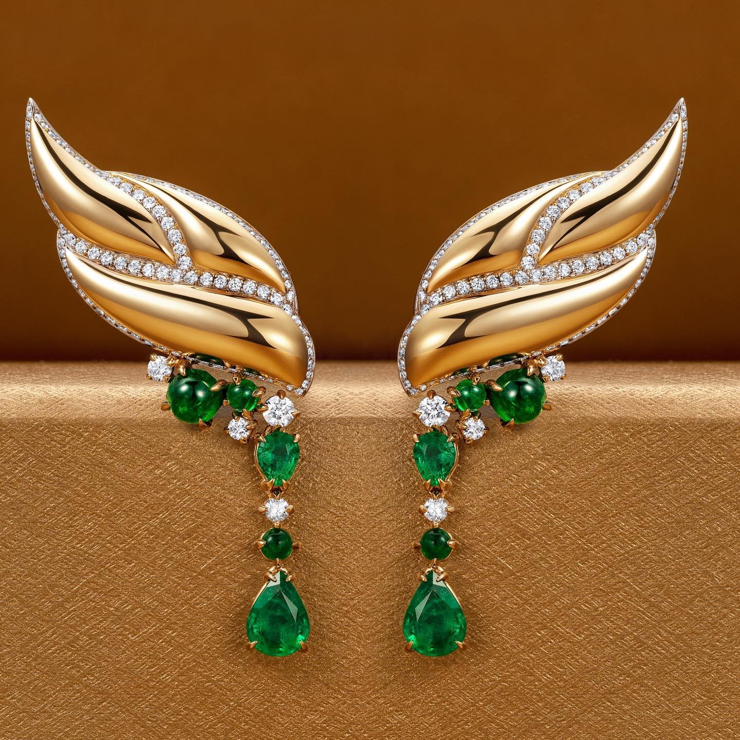 The Falcon earrings - golden feathers arch up the lobe with cascading Zambian emeralds and diamonds from their ends. 

*The Falcon, a global symbol of power, strength, and courage.
In African spirituality, a network of diverse beliefs, often associat