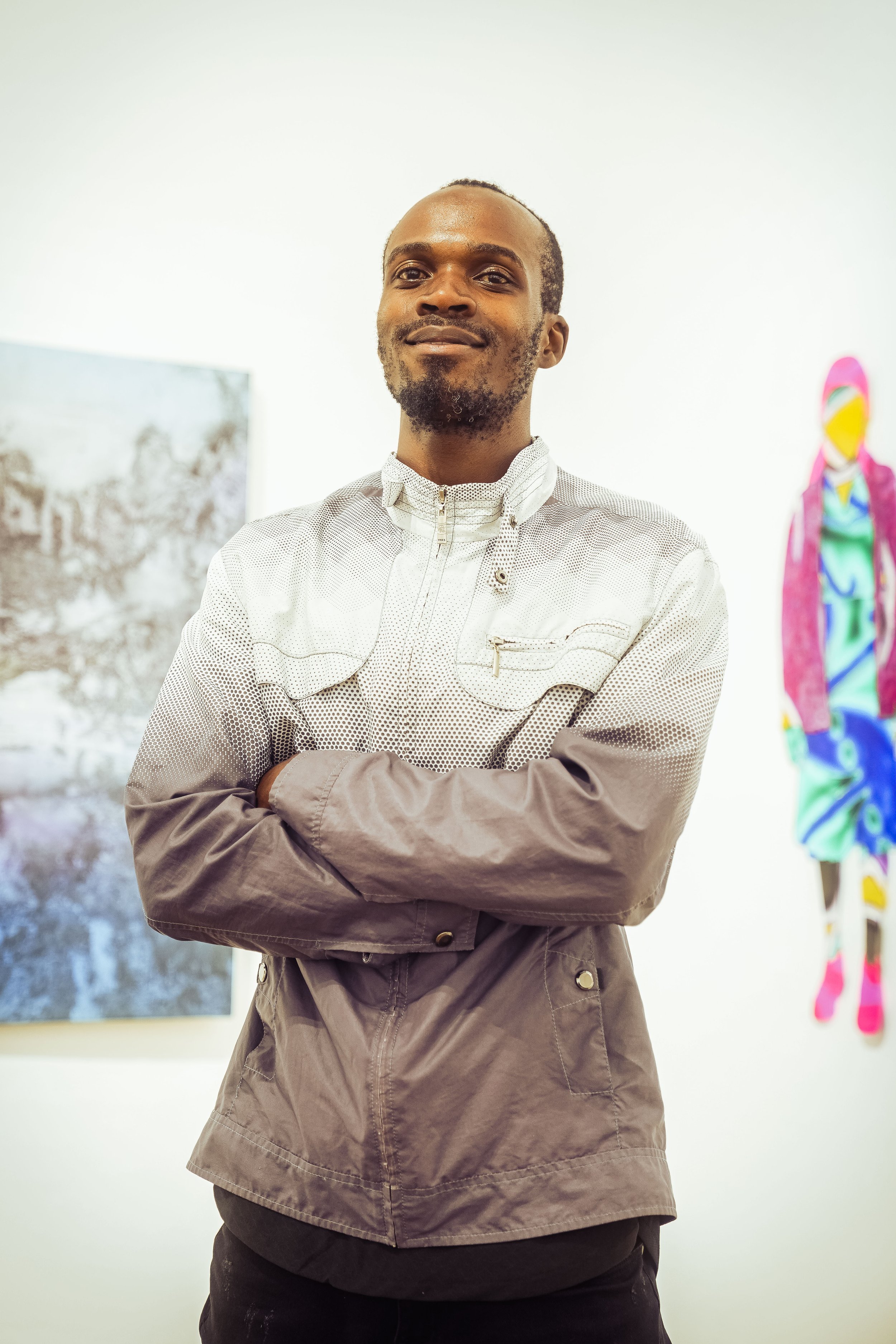 Kenyan artist StoneFace Boomba standing among artworks at African Arts Trust in Nairobi, Kenya.