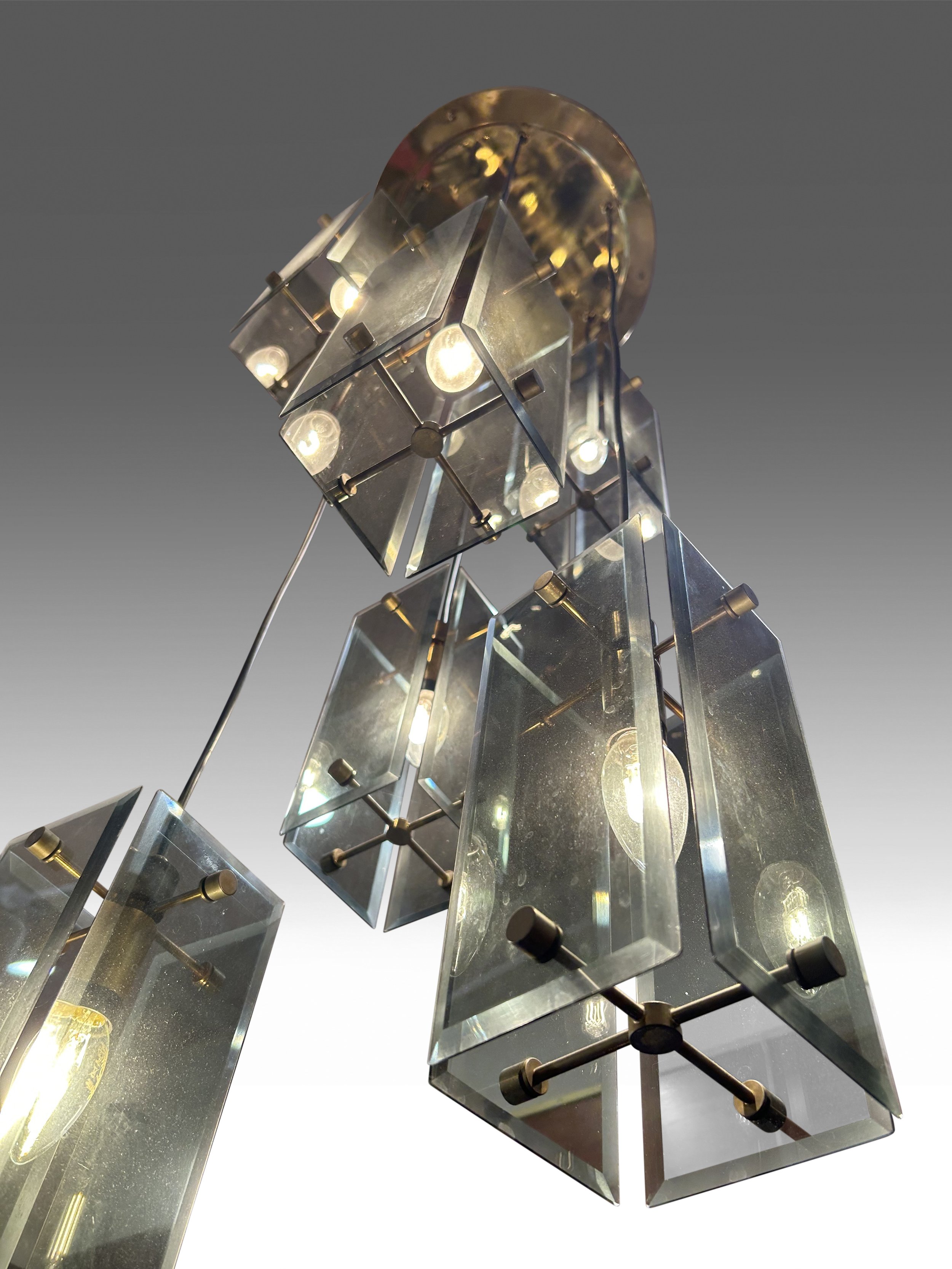 Elegant 1970s Italian chandelier by Fontana Arte, featuring a brass frame with six descending light points and beveled smoked glass shades. Inspired by Max Ingrand’s designs