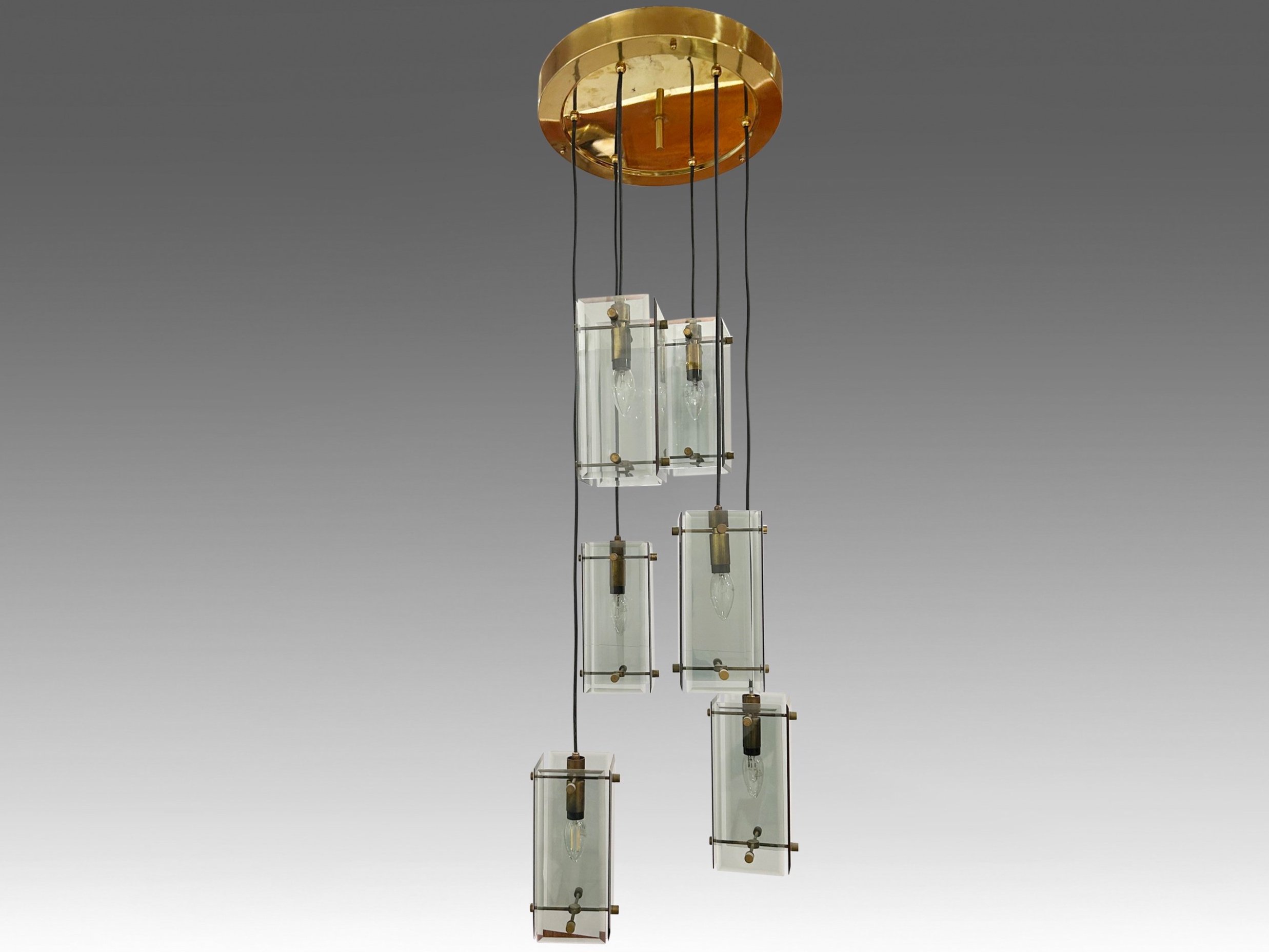 Elegant 1970s Italian chandelier by Fontana Arte, featuring a brass frame with six descending light points and beveled smoked glass shades. Inspired by Max Ingrand’s designs