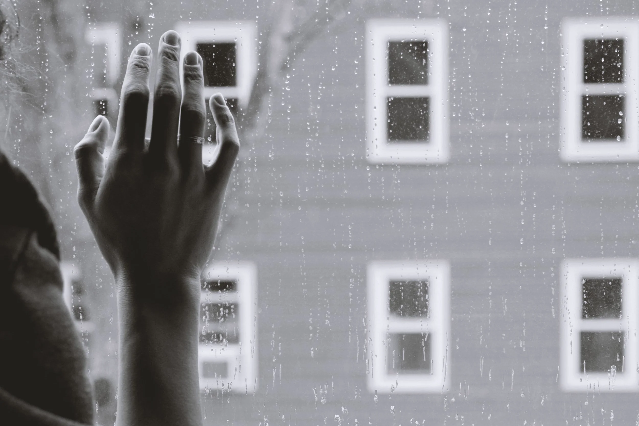 A woman looking out of a rainy window