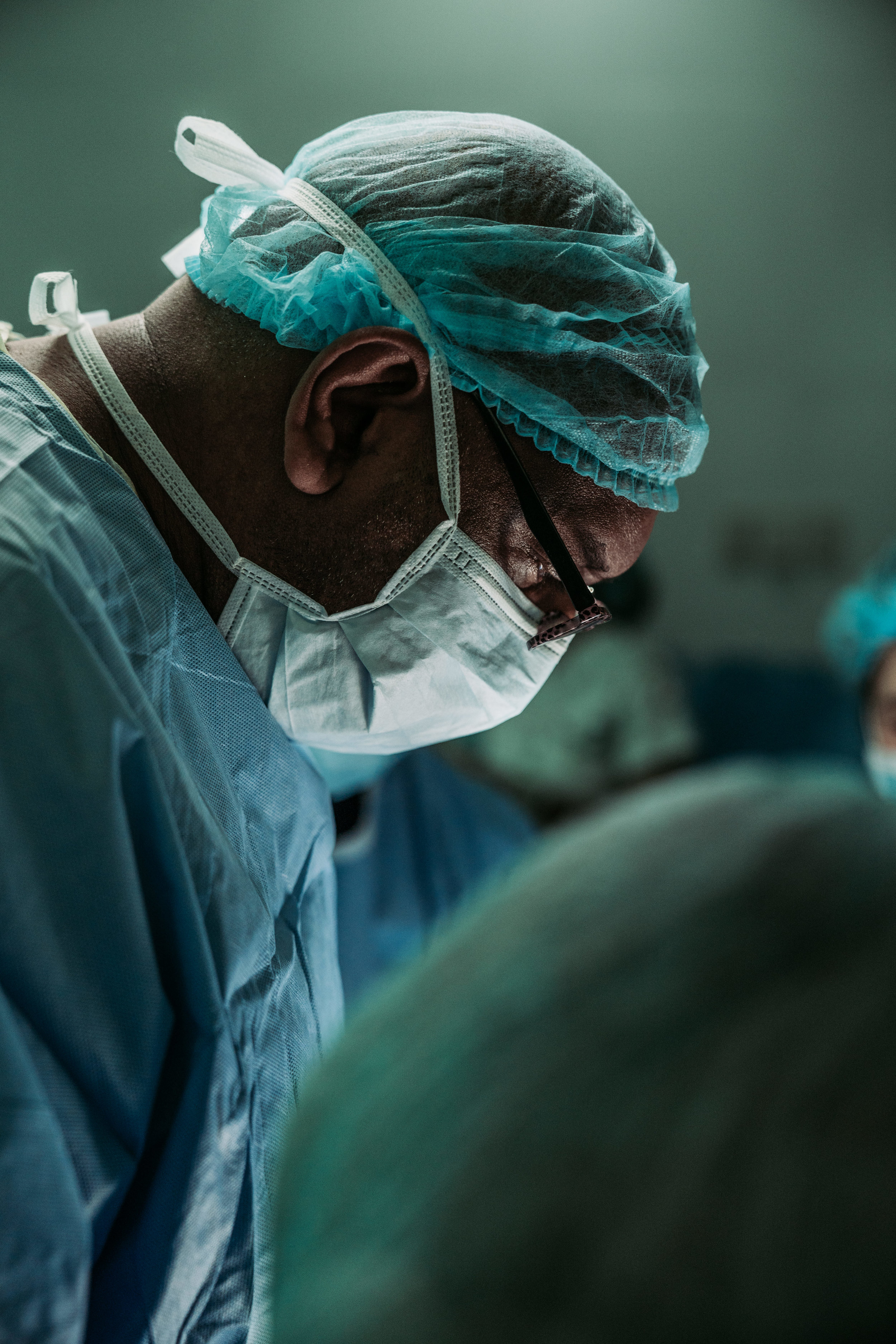 A surgeon in scrubs and mask in the operating room