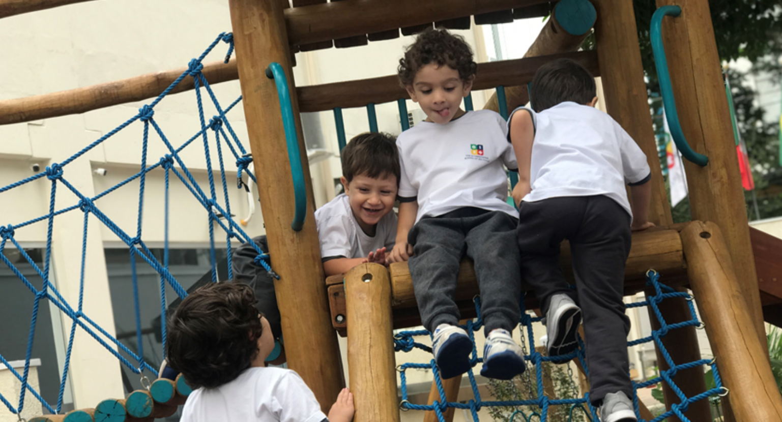 Alunos se divertem um um dos brinquedos do playground da área externa da escola.