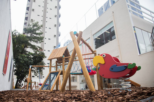 Área externa e aberta da escola com várias opções de brinquedos.