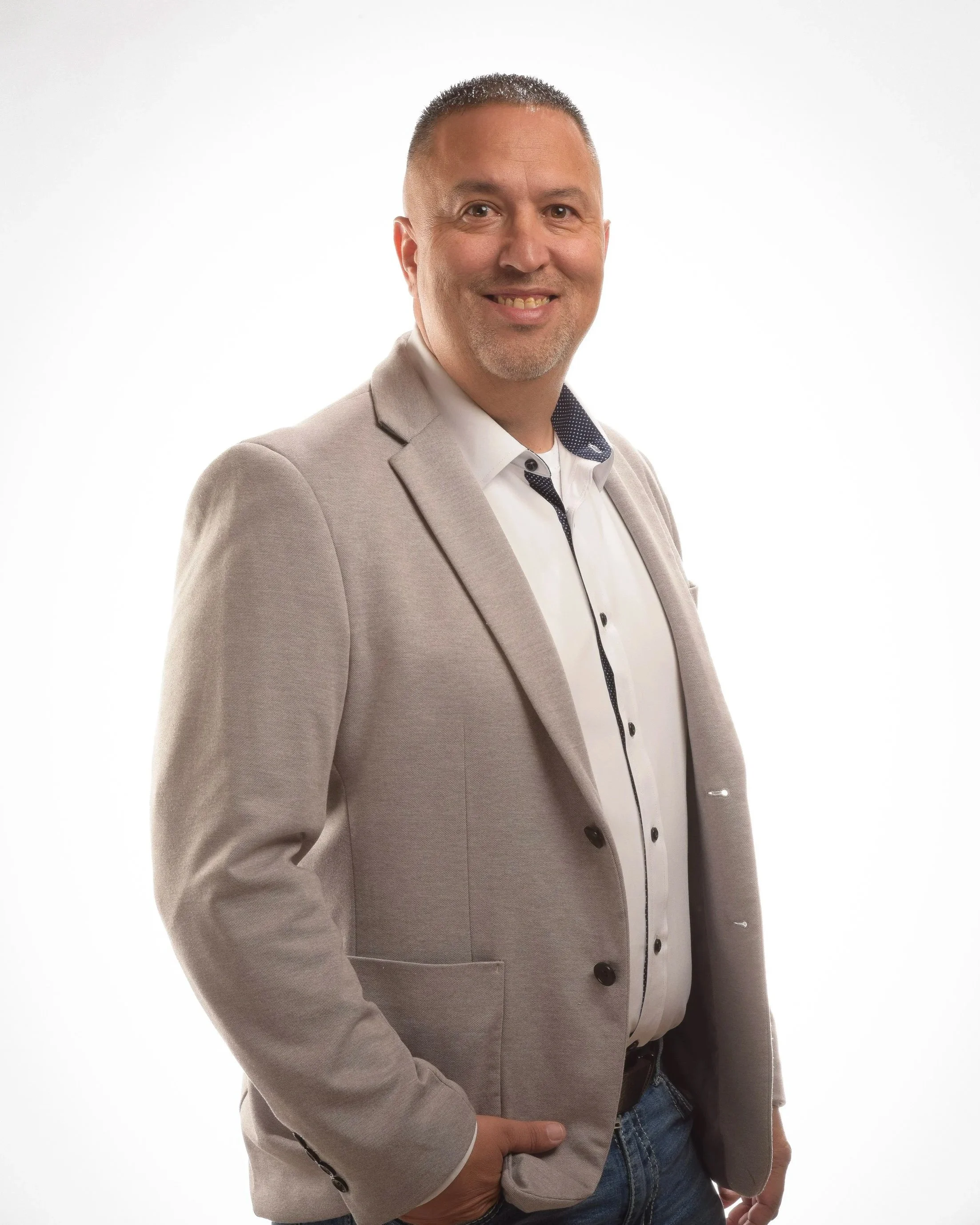 An image of a middle aged man with a buzz cut. He is wearing a grey suit.
