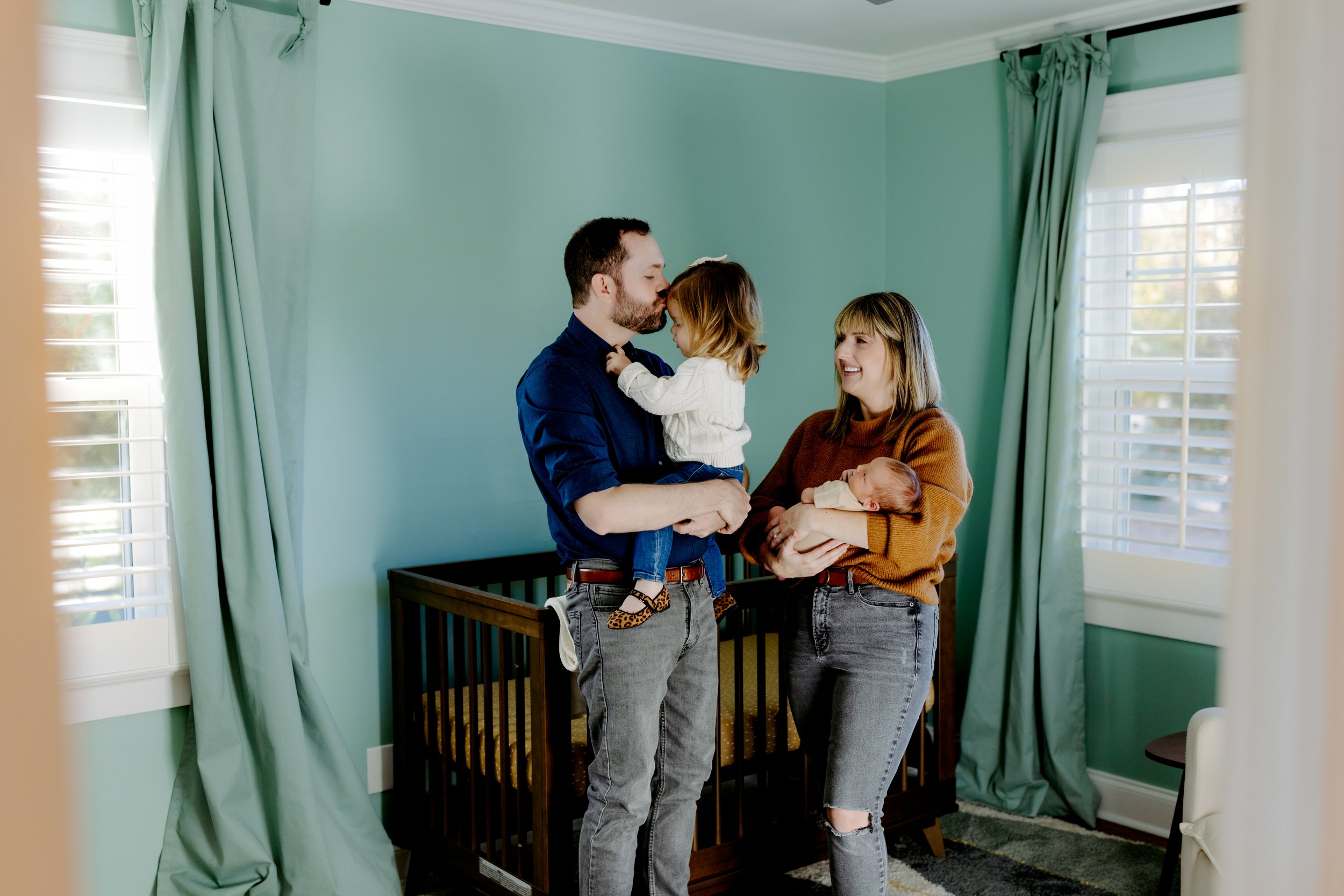 family of four together in the baby’s nursery during a warm natural light newborn photography at home