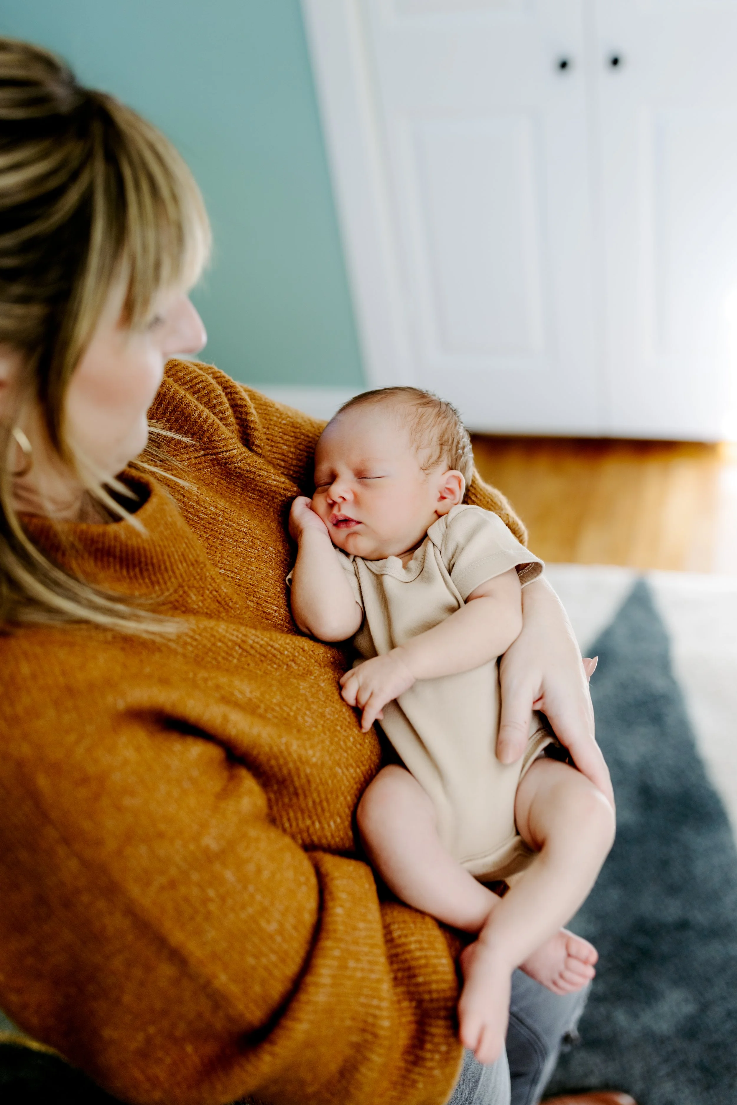 In home newborn photos featuring mother holding sleeping newborn