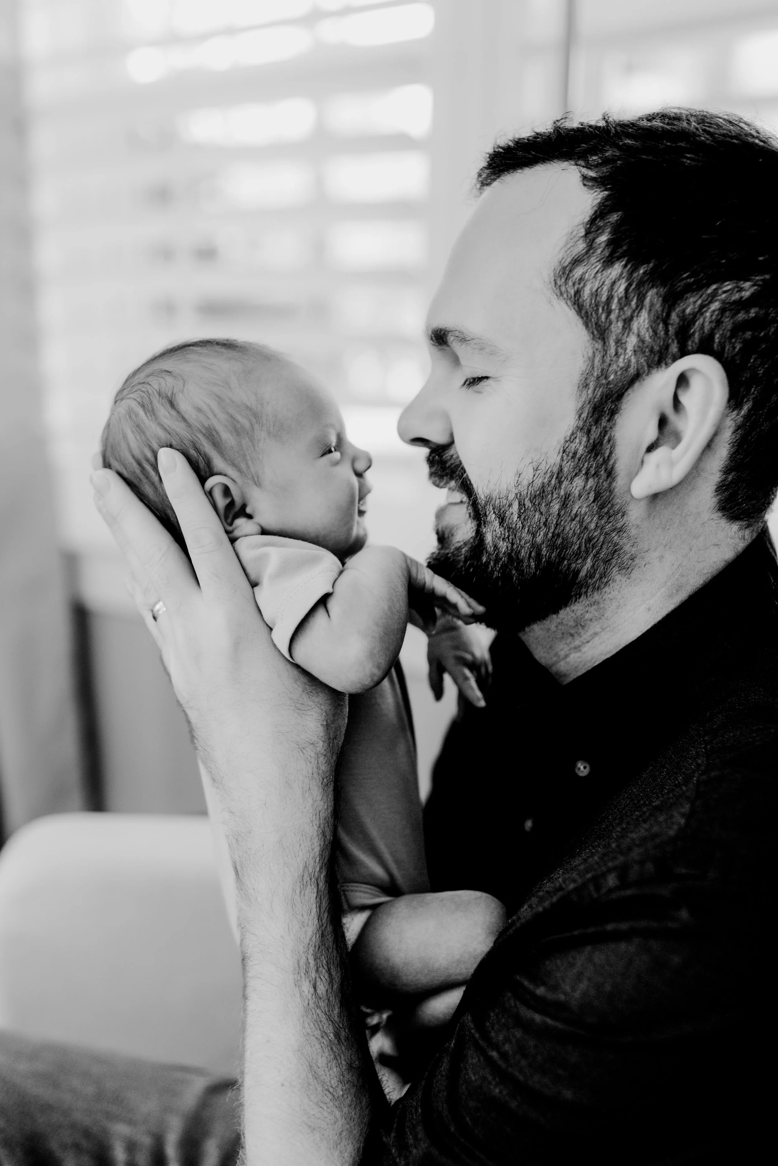 dad holding newborn baby boy nose to nose