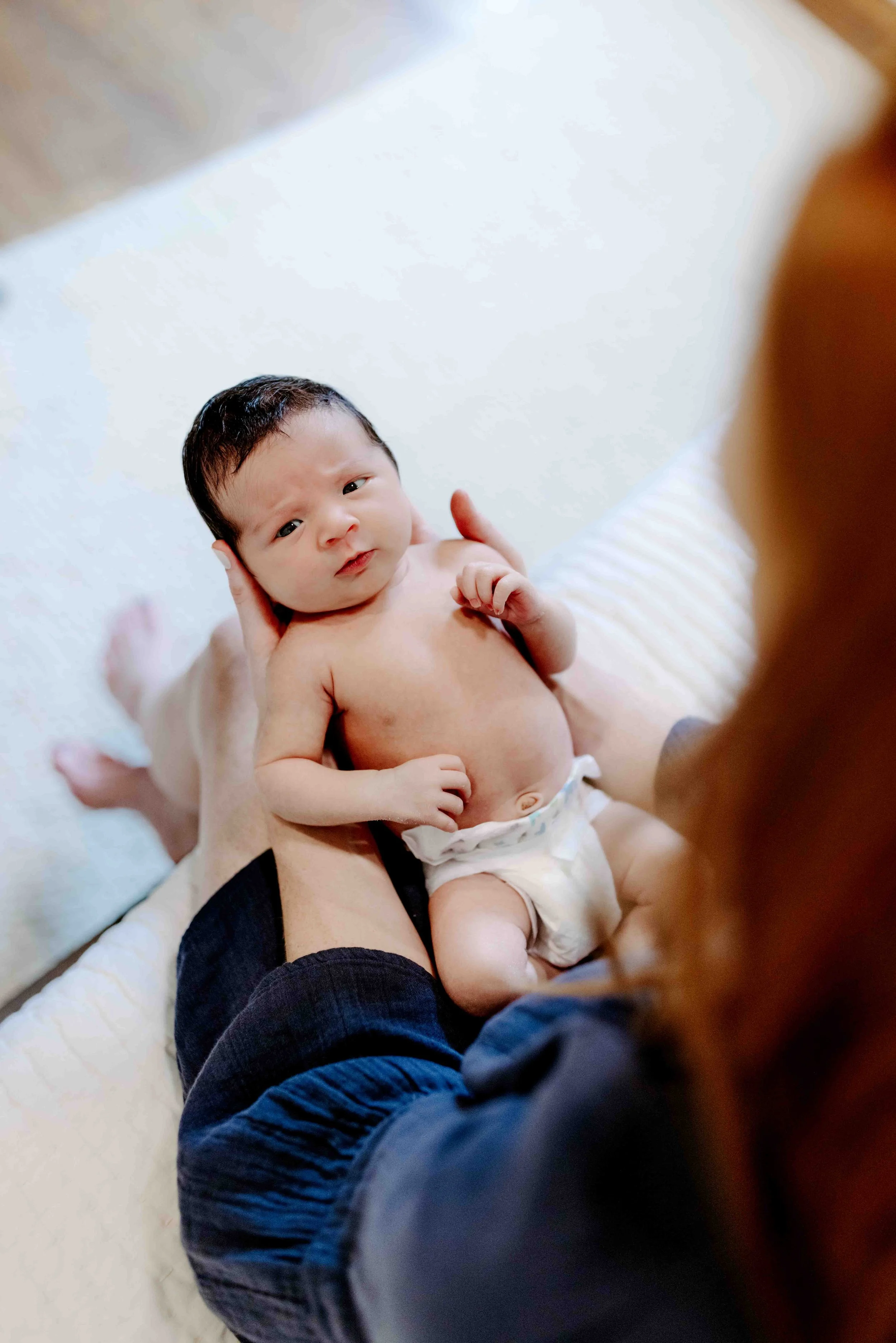 close-up of newborn baby boy in diaper being held by mom
