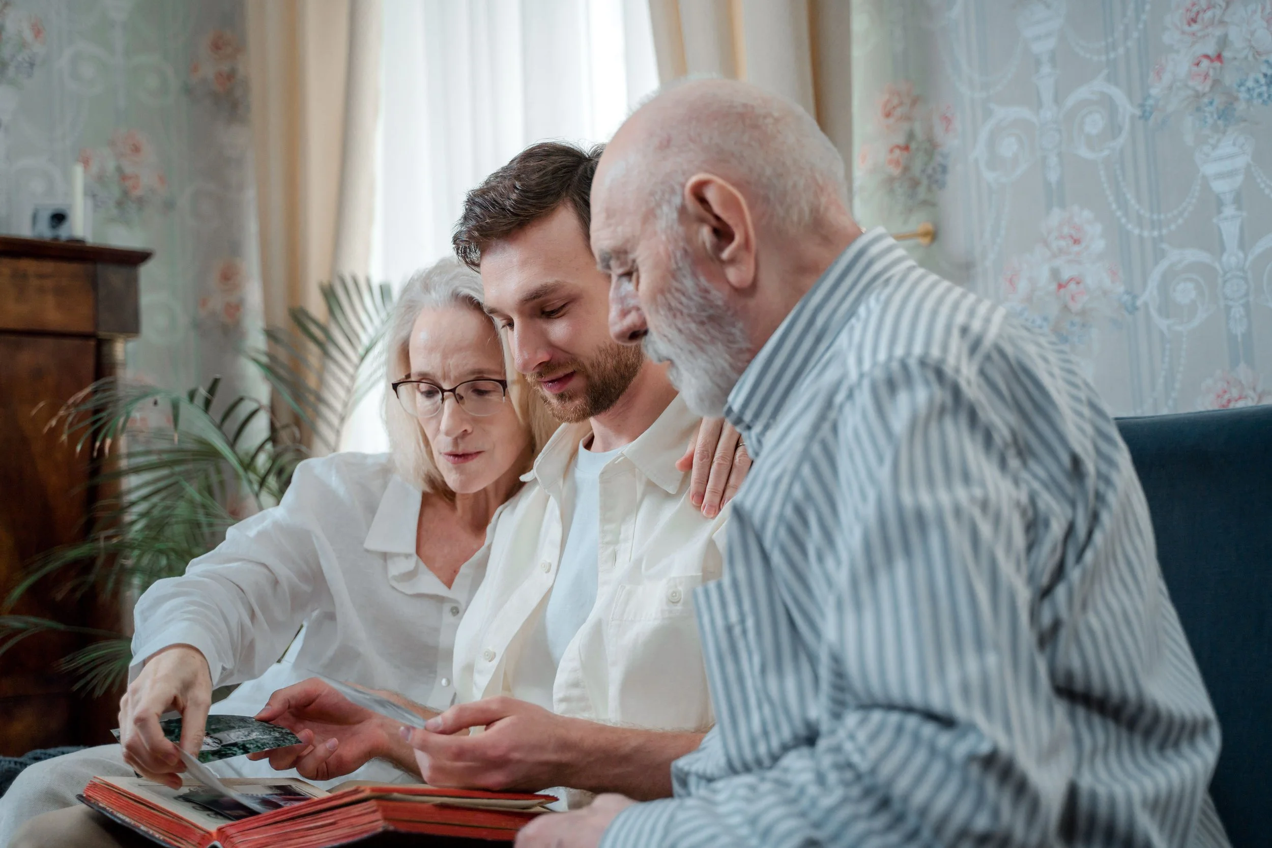 Family members sitting together, looking through printed photographs and a family photo album.