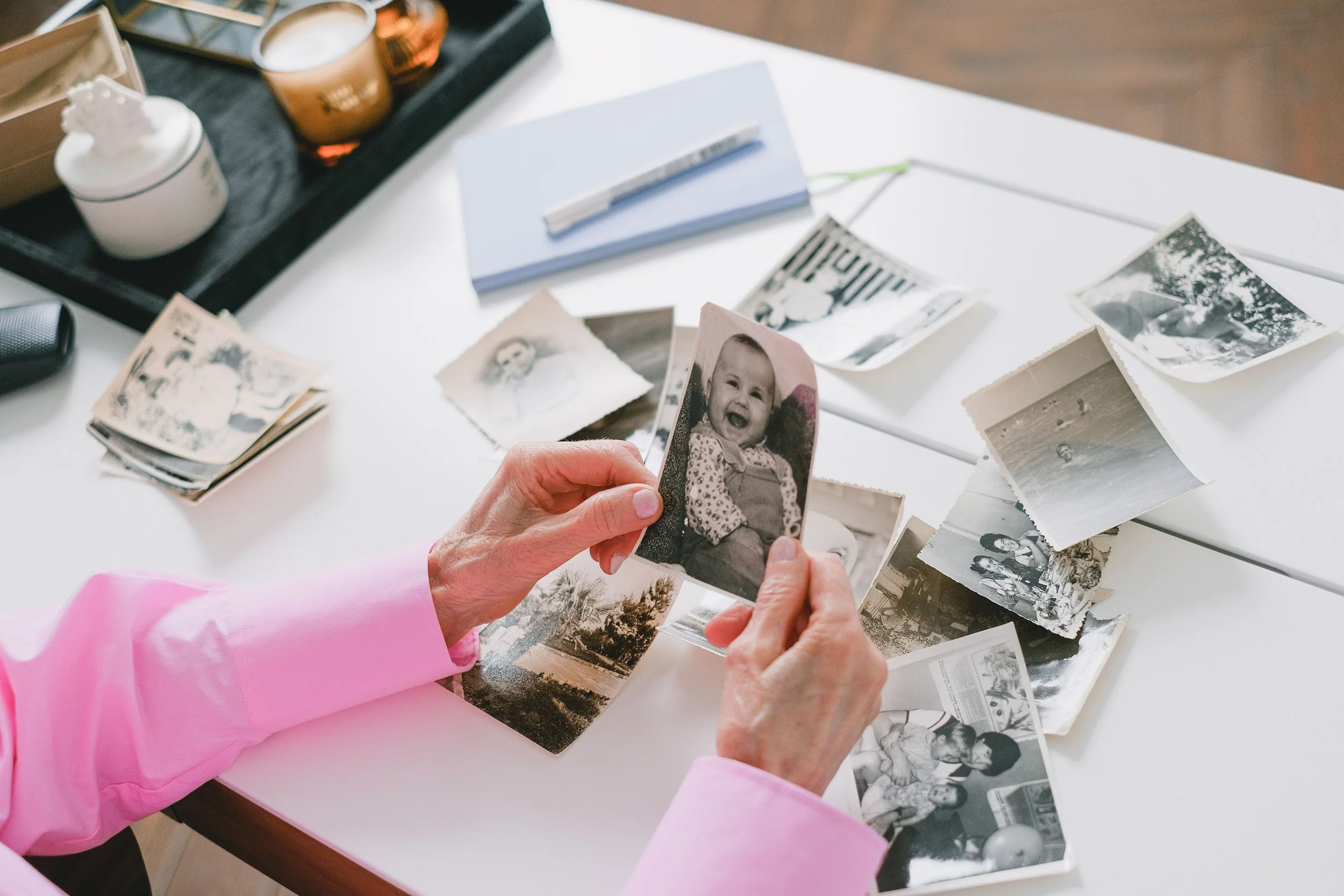 Hands sorting treasured family photographs, illustrating how a thoughtful organizing system builds trust, protects memories, and brings peace of mind.