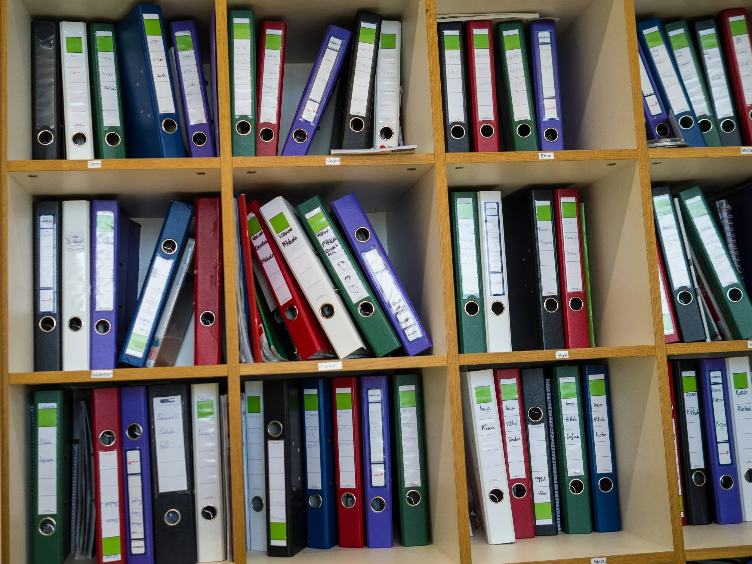 Colorful labeled binders on shelves, showing a simple system to organize overwhelming paperwork.