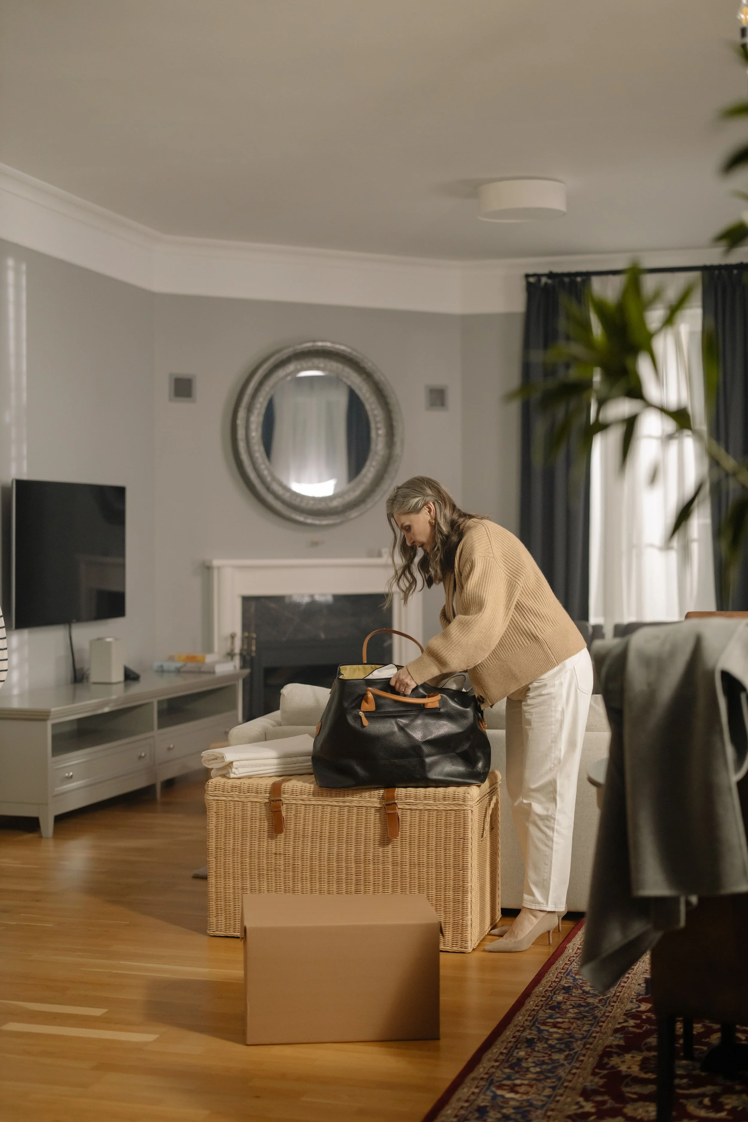 Older woman organizing belongings in a calm, tidy living room during a life transition.