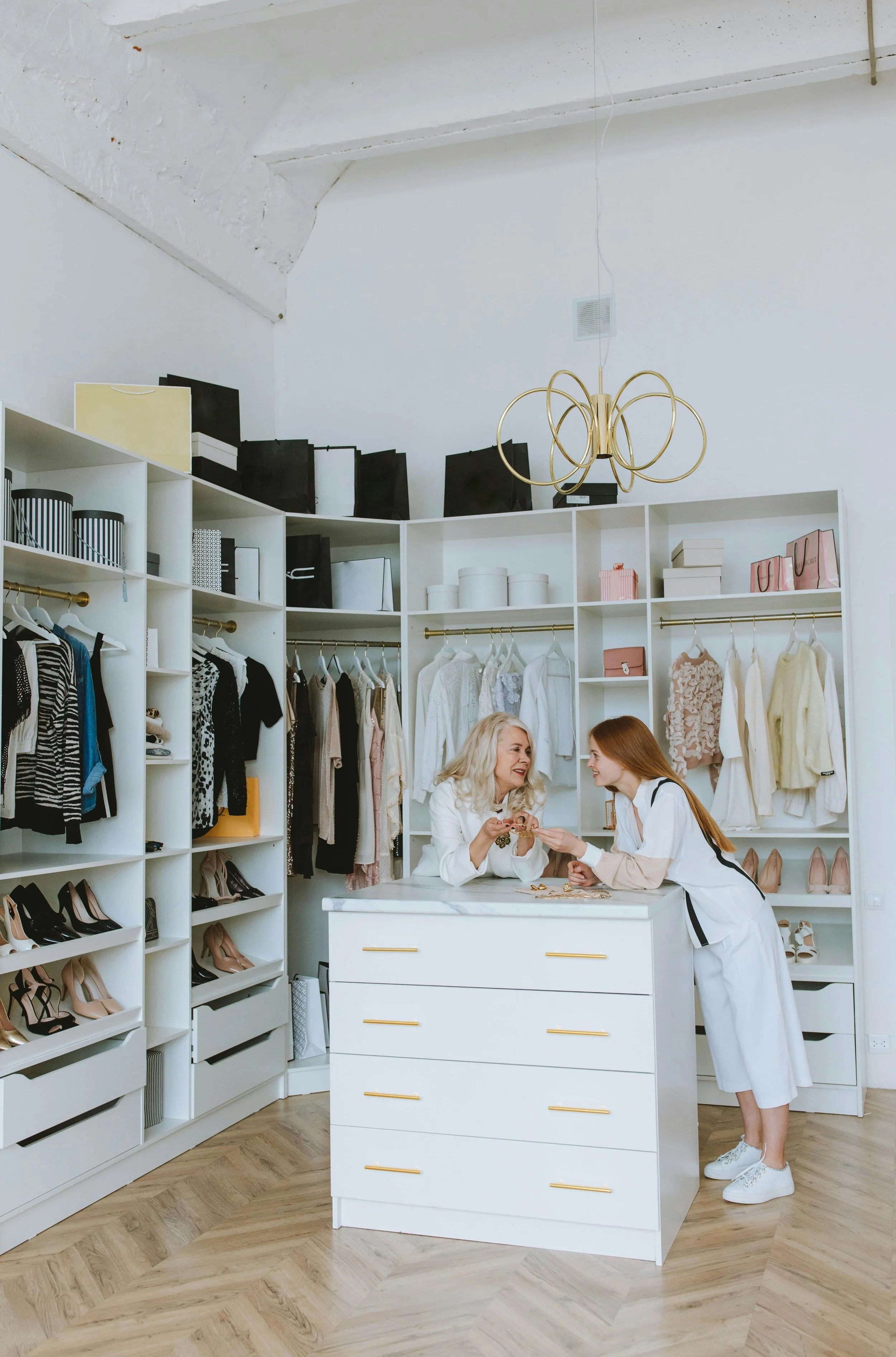 Professional organizer warmly consulting with a client in a beautifully organized walk-in closet, creating personalized systems that support the client's unique needs and lifestyle.
