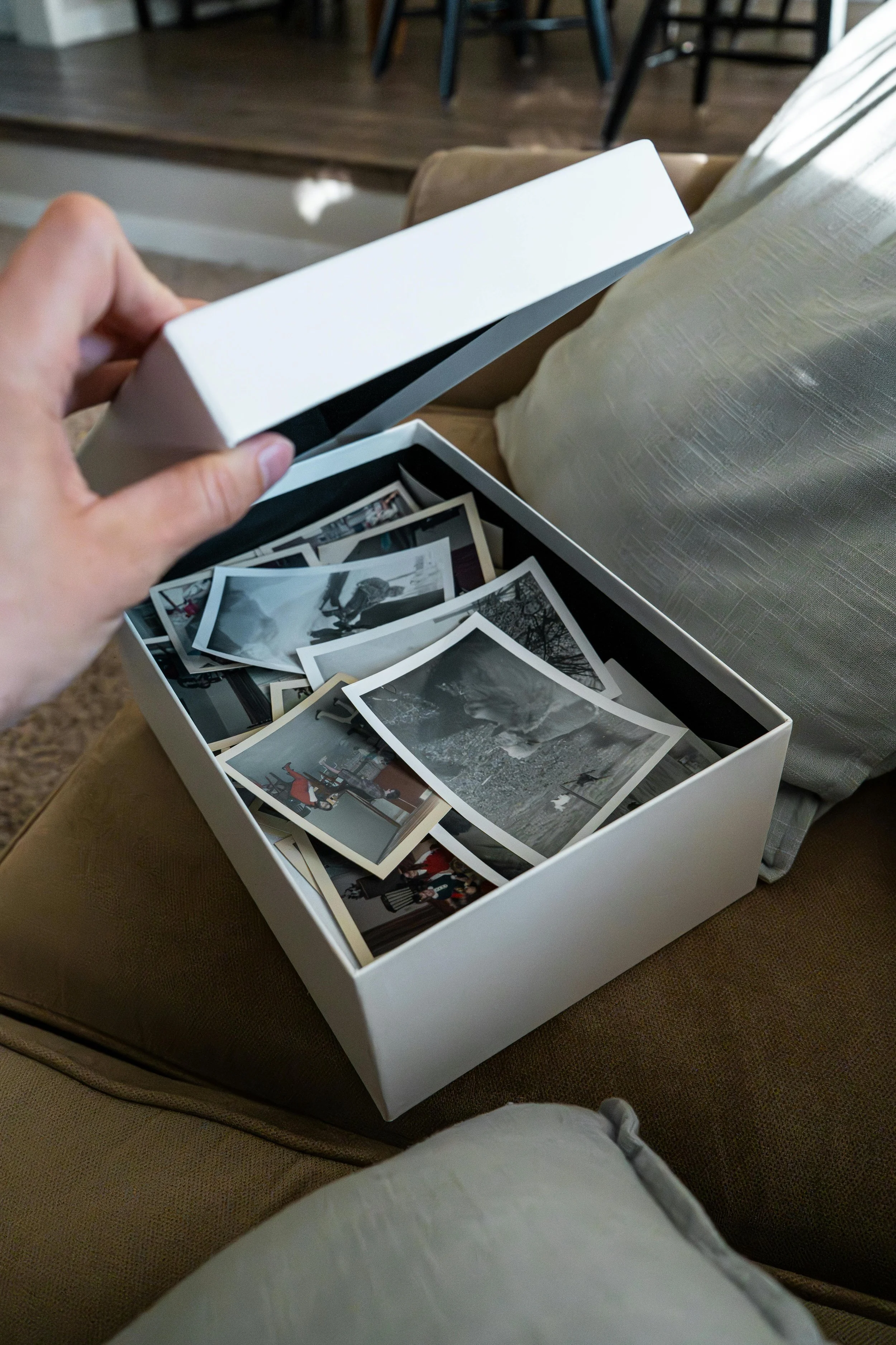 Hand opening a safe storage box filled with treasured family photographs, preserving memories