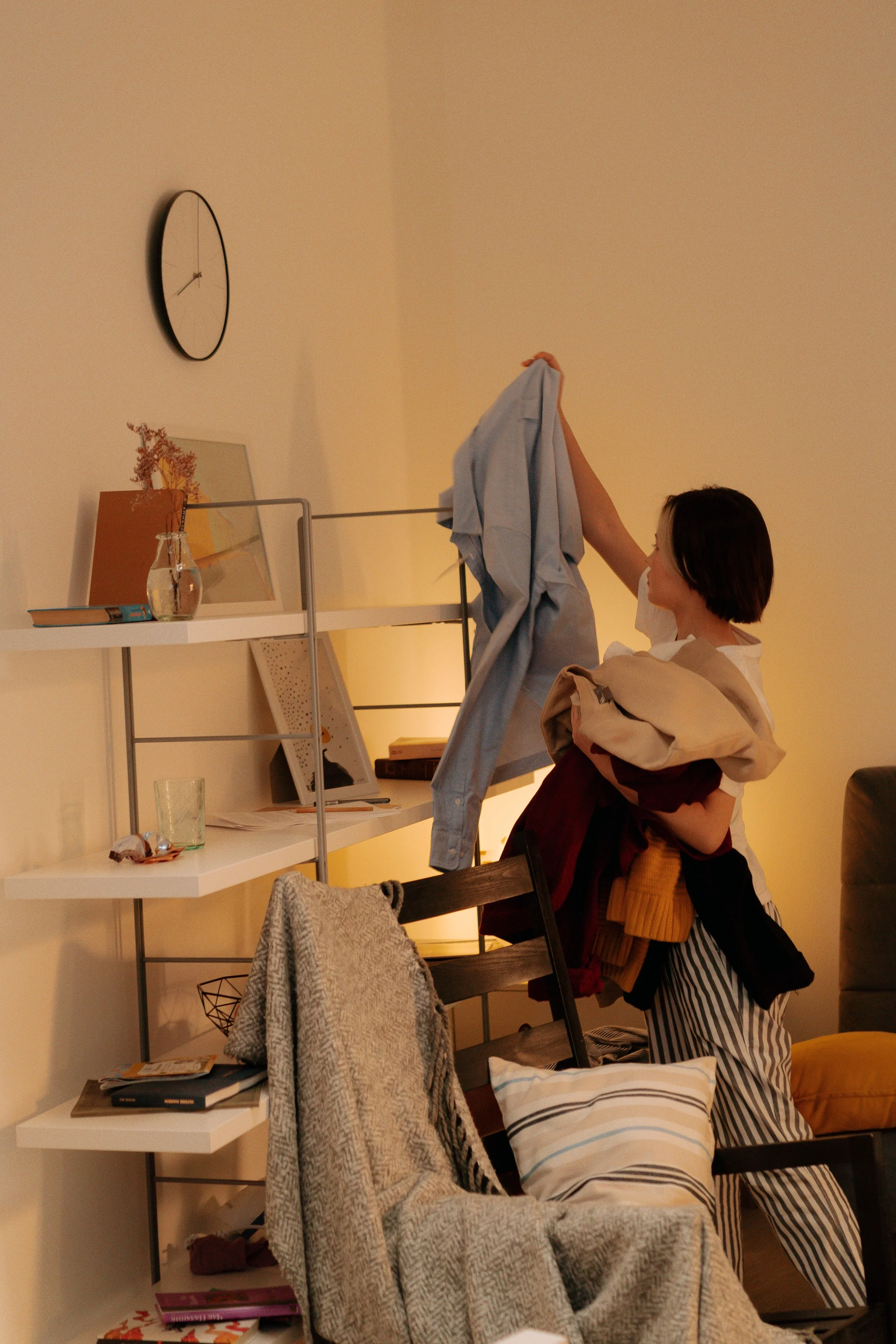 Woman sorting clothes while decluttering and organizing a living room.