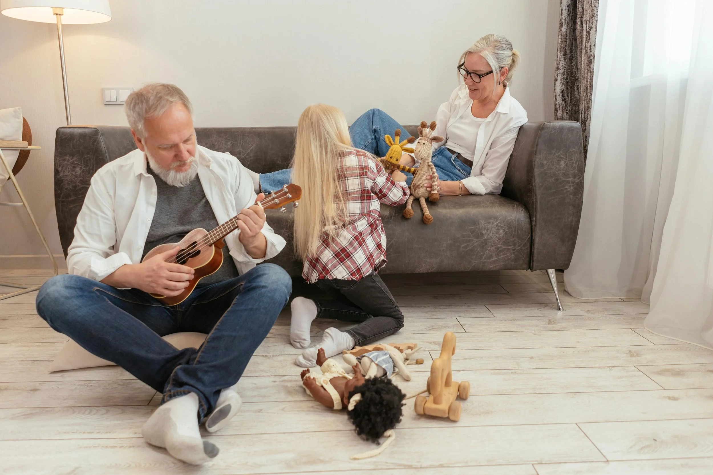 A warm family playtime scene with grandparents and child enjoying toys together in a cozy living room, reflecting how love-filled gifts can overflow a home and inspire the need for calm, organized spaces.