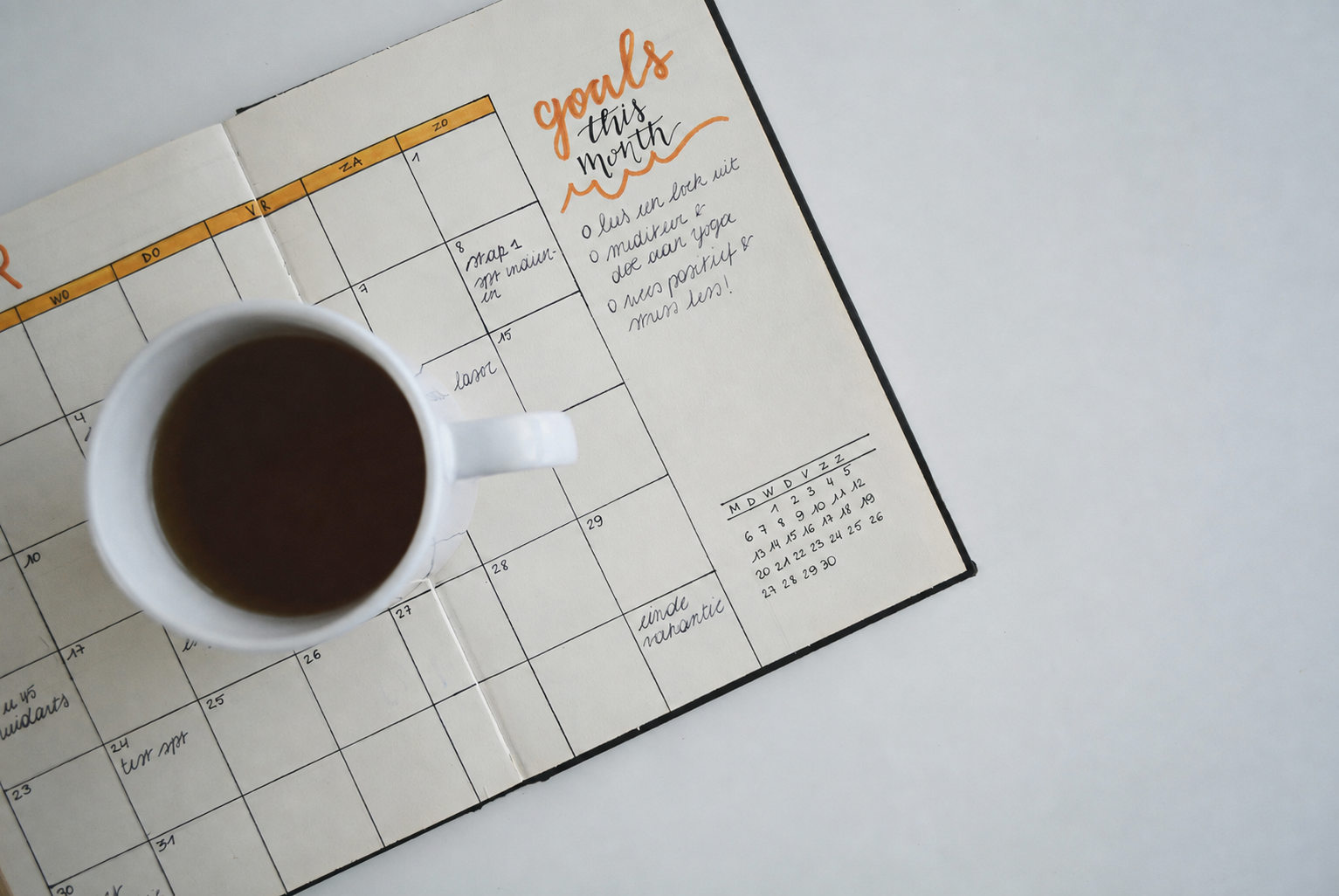 Open planner with coffee cup, representing intentional calendar organization and making time for what matters.