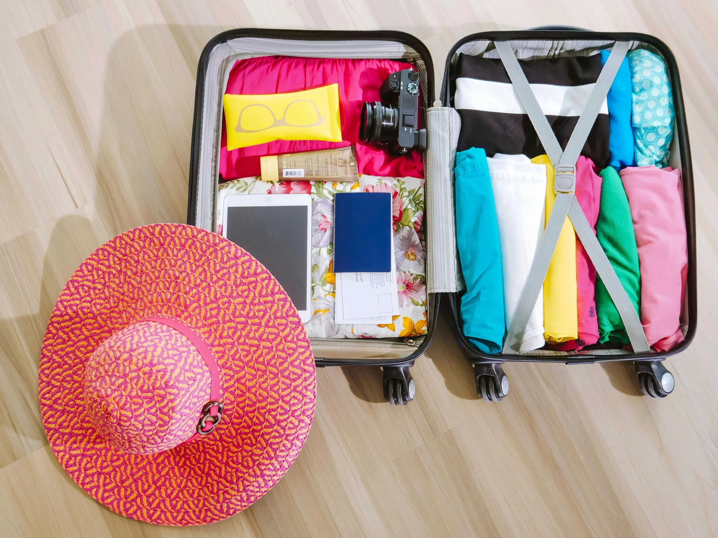 Open suitcase with neatly packed colorful clothing and travel essentials, showing how organized systems make vacation packing easier and help prevent rebuying items you already own.