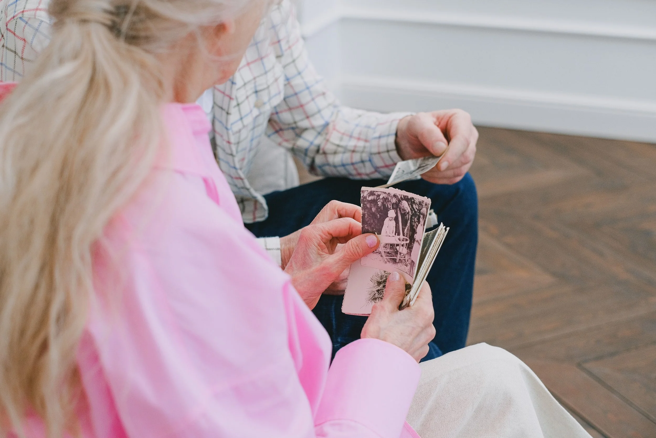Two older adults looking through vintage family photographs together.