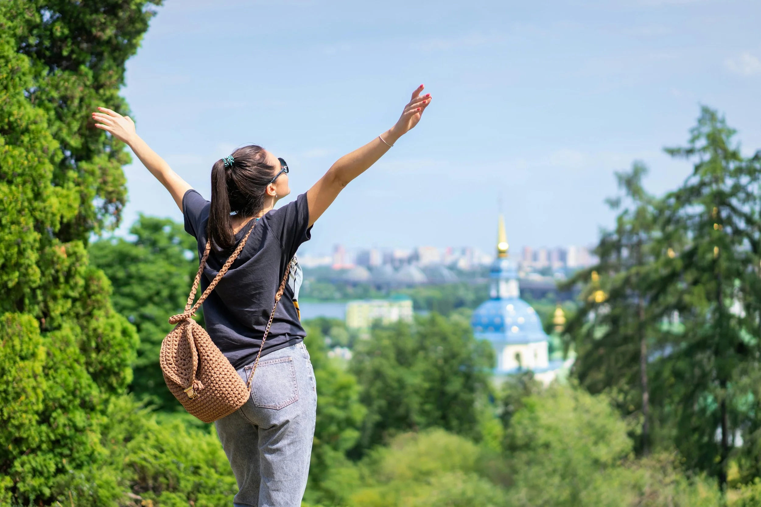 Woman joyfully walking in fresh air with arms open, celebrating the light, peaceful feeling that comes after decluttering and creating space in life and home.