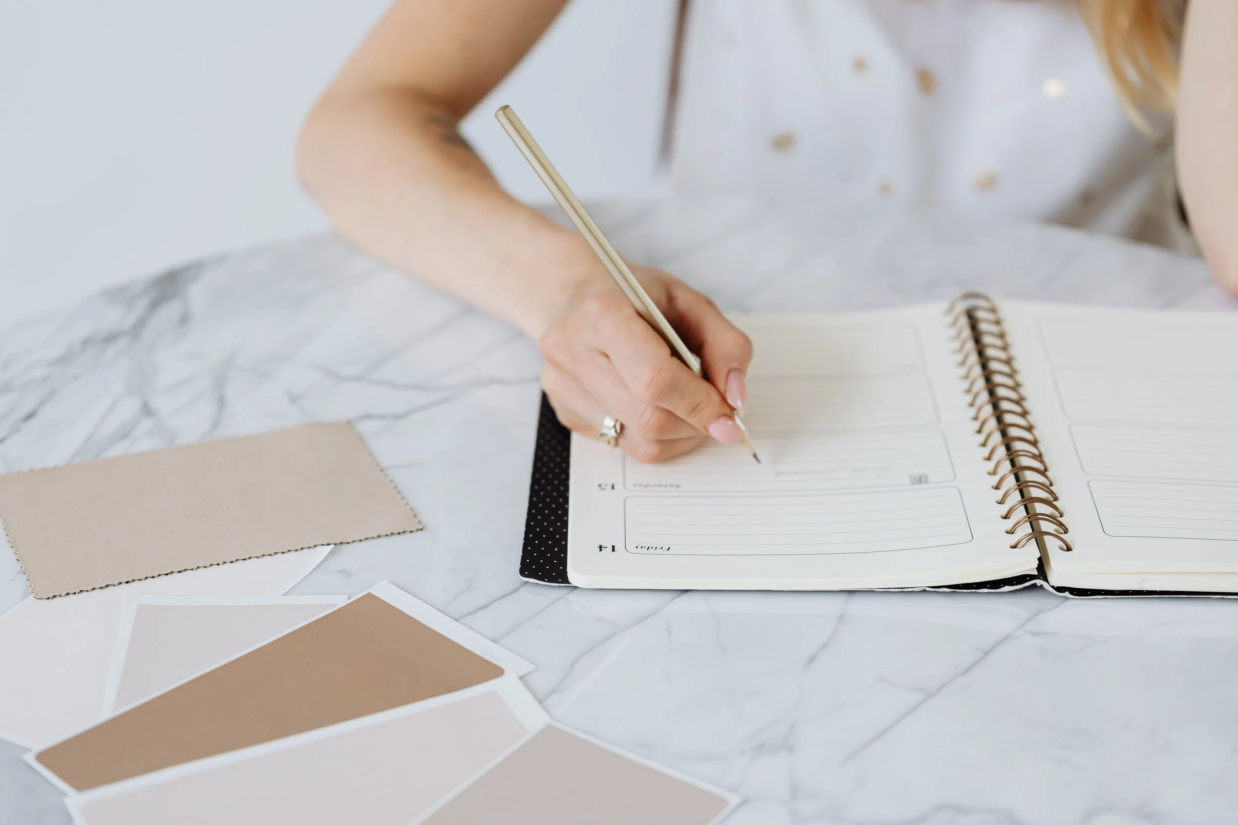 Person writing in a planner while intentionally organizing a calendar to make time for priorities and a more balanced life.