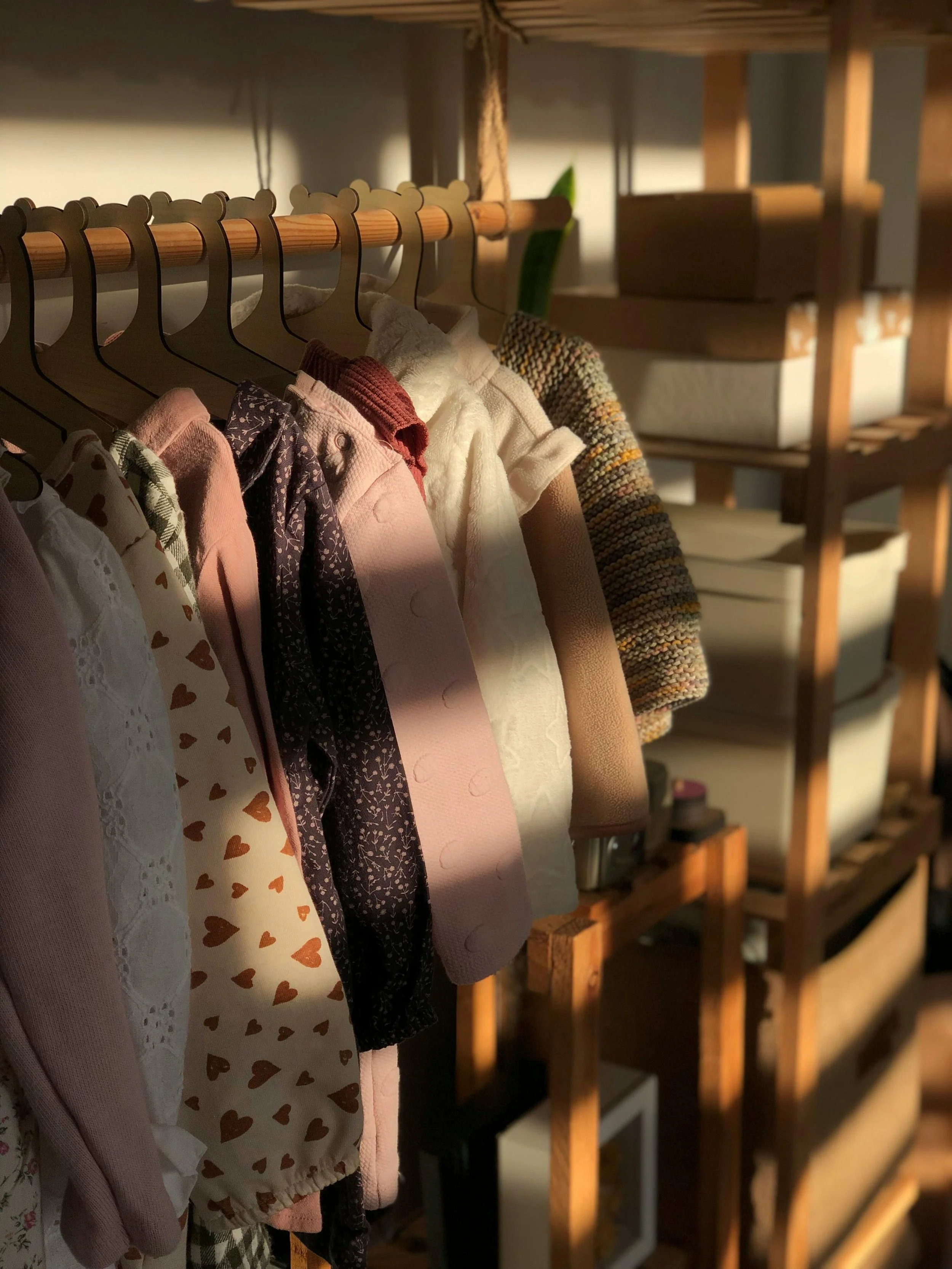 Softly lit children’s clothes neatly organized by size and category, creating calm and ease in a busy family routine.