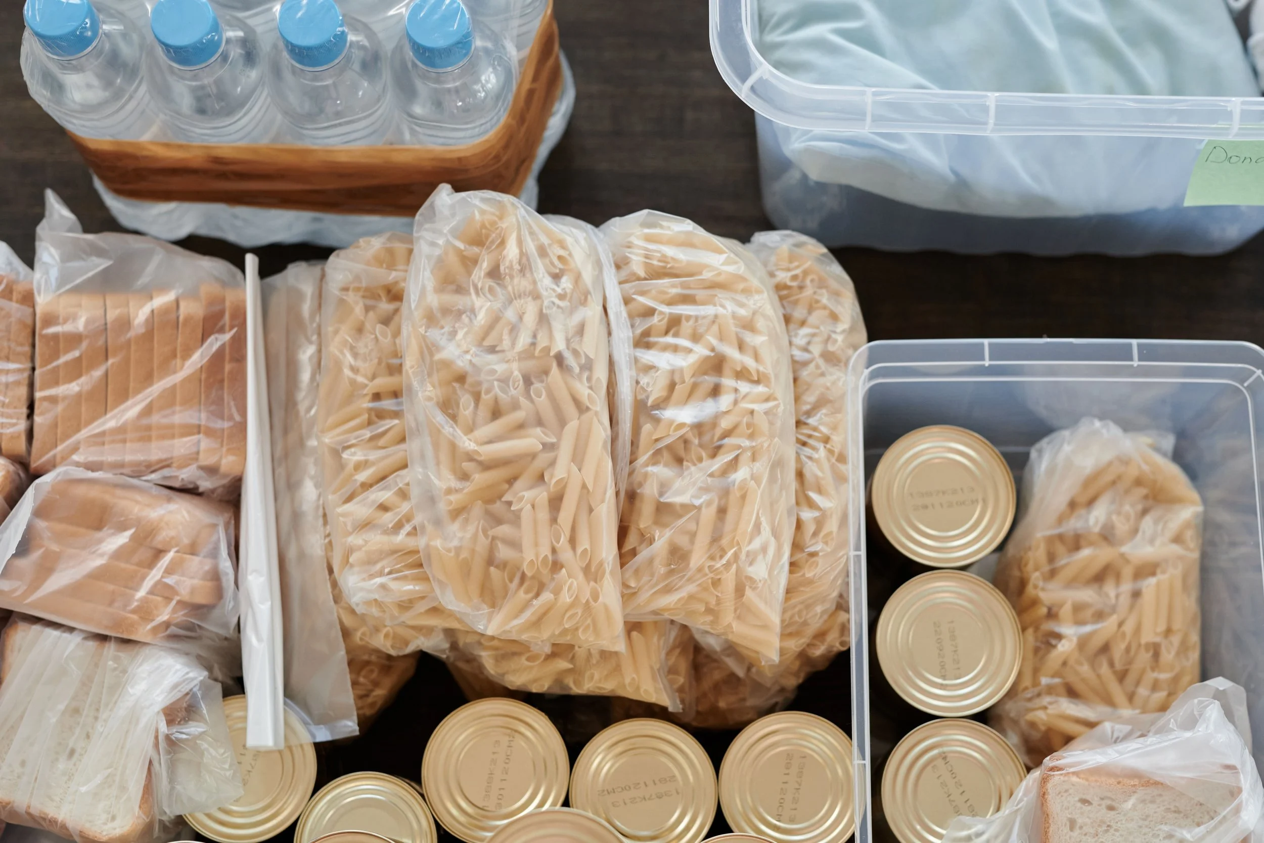 Organized bulk food supplies, bread, canned goods, and bottled water stored in labeled bins, illustrating how buying in bulk works best when every item has a designated storage space.