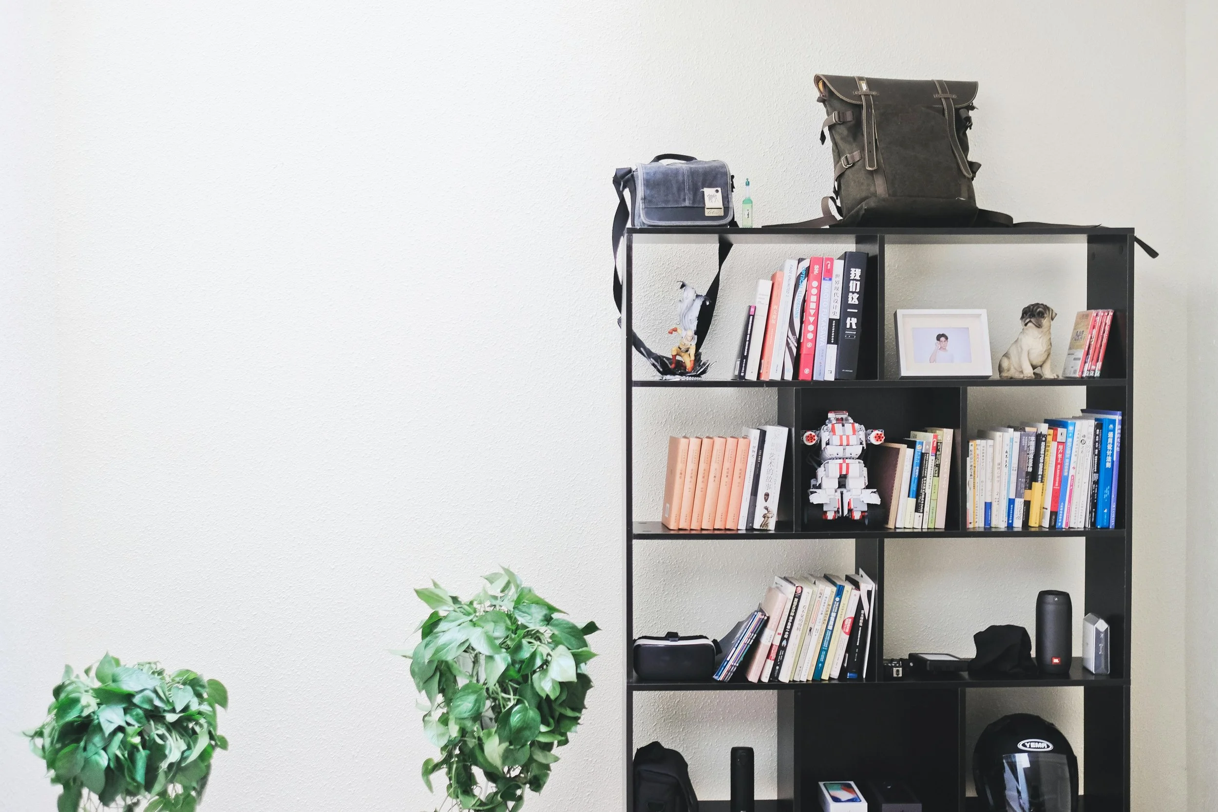 Neatly styled black cube bookshelf with books, bags and small décor items against a clean white wall.