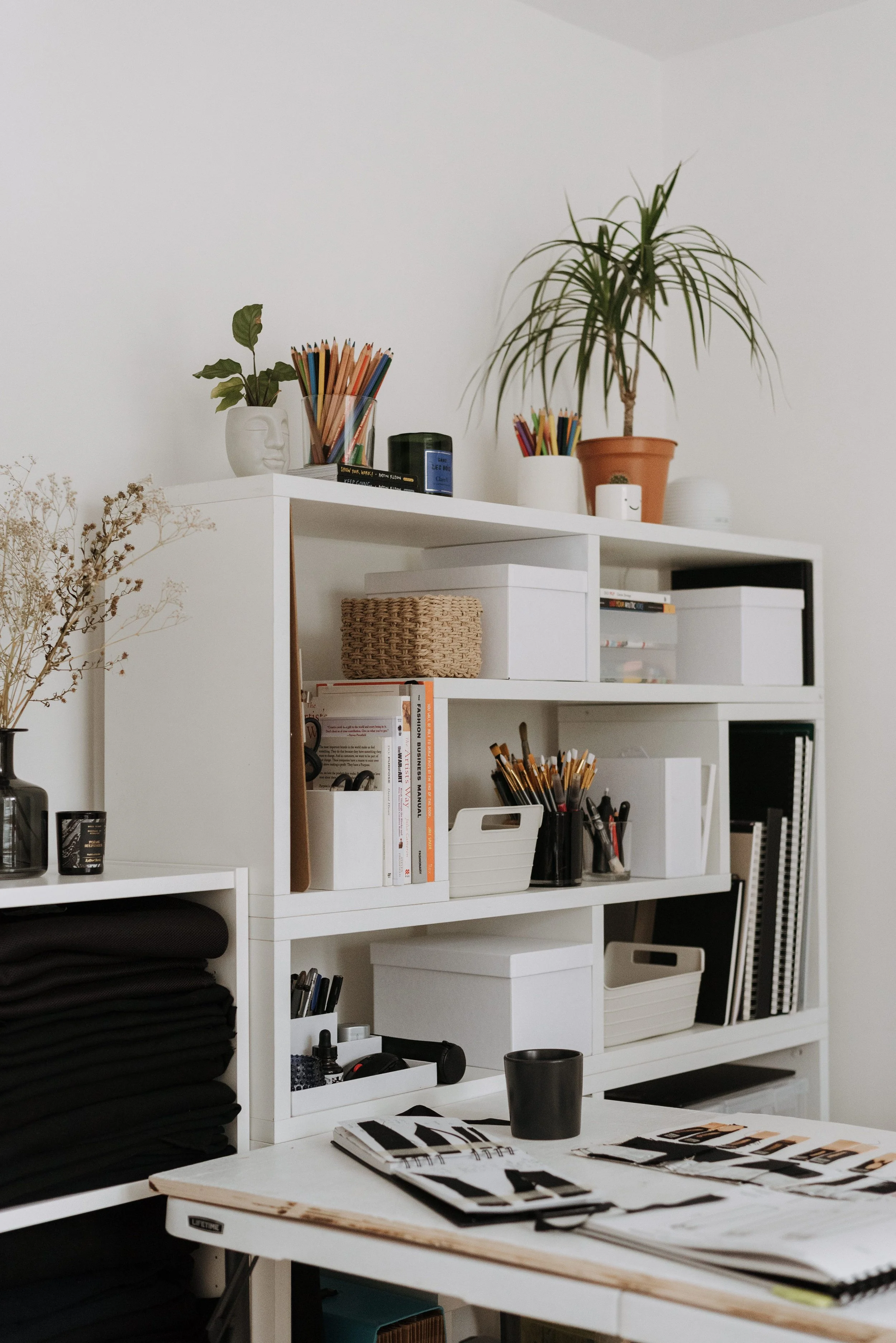 Organized artist’s studio with neatly arranged supplies, labeled storage boxes, sketchbooks, brushes, and creative tools—an inspiring space designed to reduce overwhelm and support creativity.