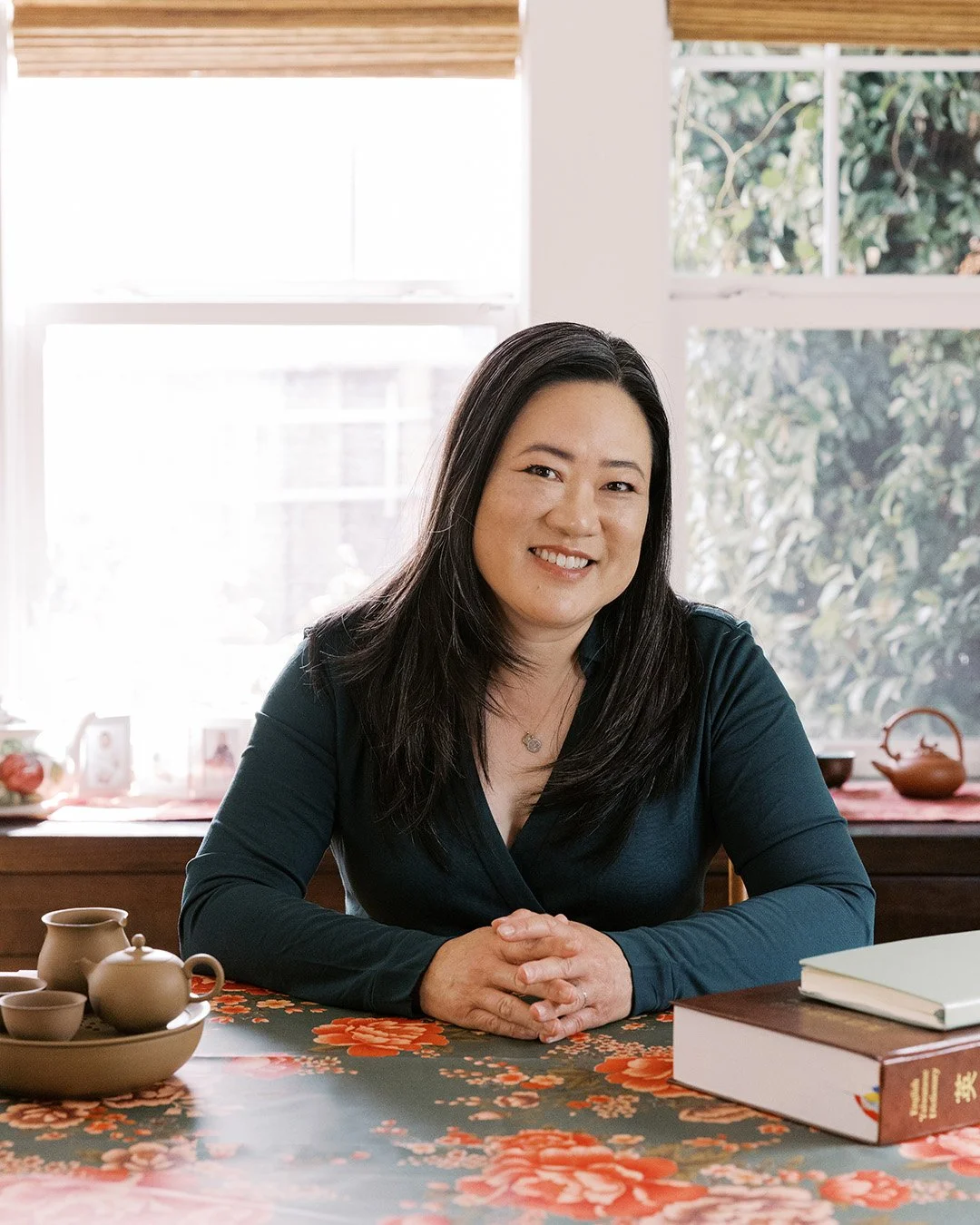 Asian woman wearing green dress with a dictionary and tea set
