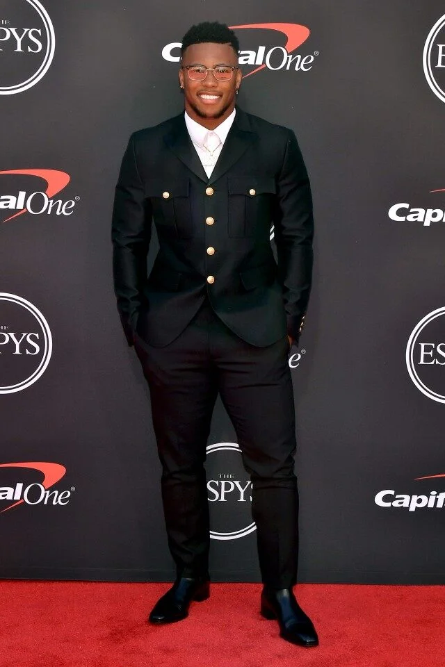 Best Breakthrough Athlete of The Year recipient Saquon Barkley from the NY Giants, rocks this black field jacket inspired tuxedo by DSquared2 with large gold buttons.