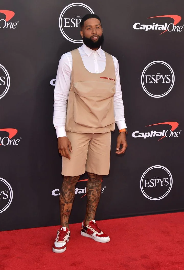 Odell Beckham, Jr. stunned everyone with his new look by ridding himself of his signature gold locs and going for a dark caesar. In this Prada ensemble with sneakers by Dominic Ciambrone aka The Shoe Surgeon .