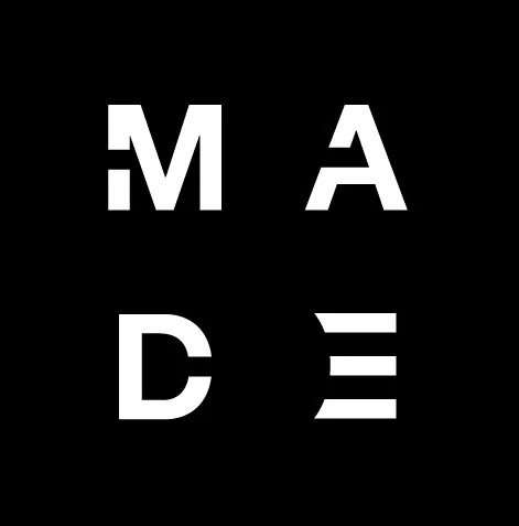 Black background with white capital letters 'M,' 'A,' 'D,' and 'E' arranged in a grid.