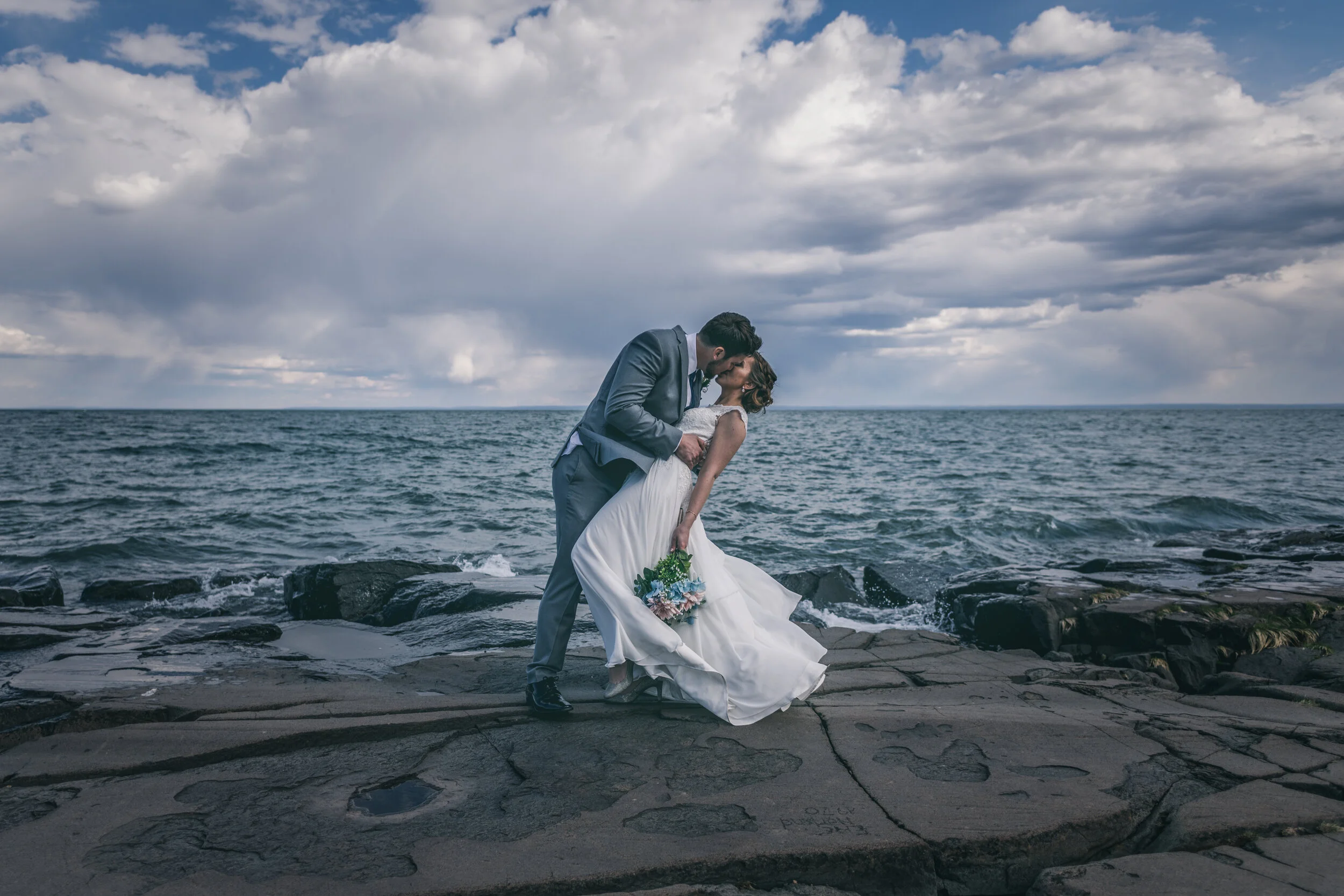 Bride and groom kissing on the rocks of Lake Superior at Brighton Beach in Duluth, MN