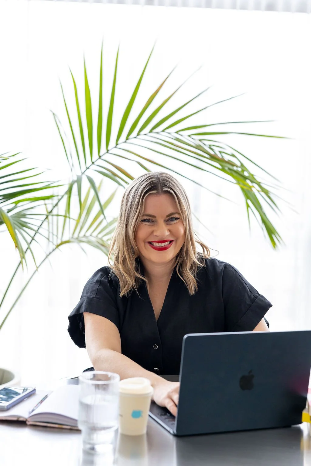 Portrait of Bec Sands, working at her desk, smiling