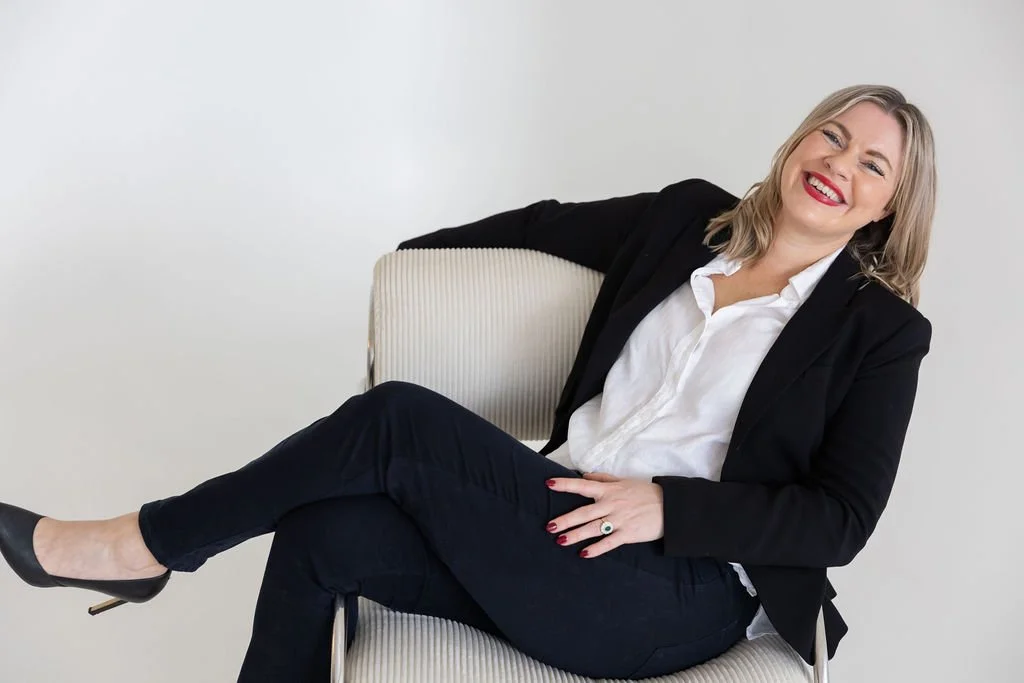 Portrait of Bec Sands, reclining in an armchair and smiling