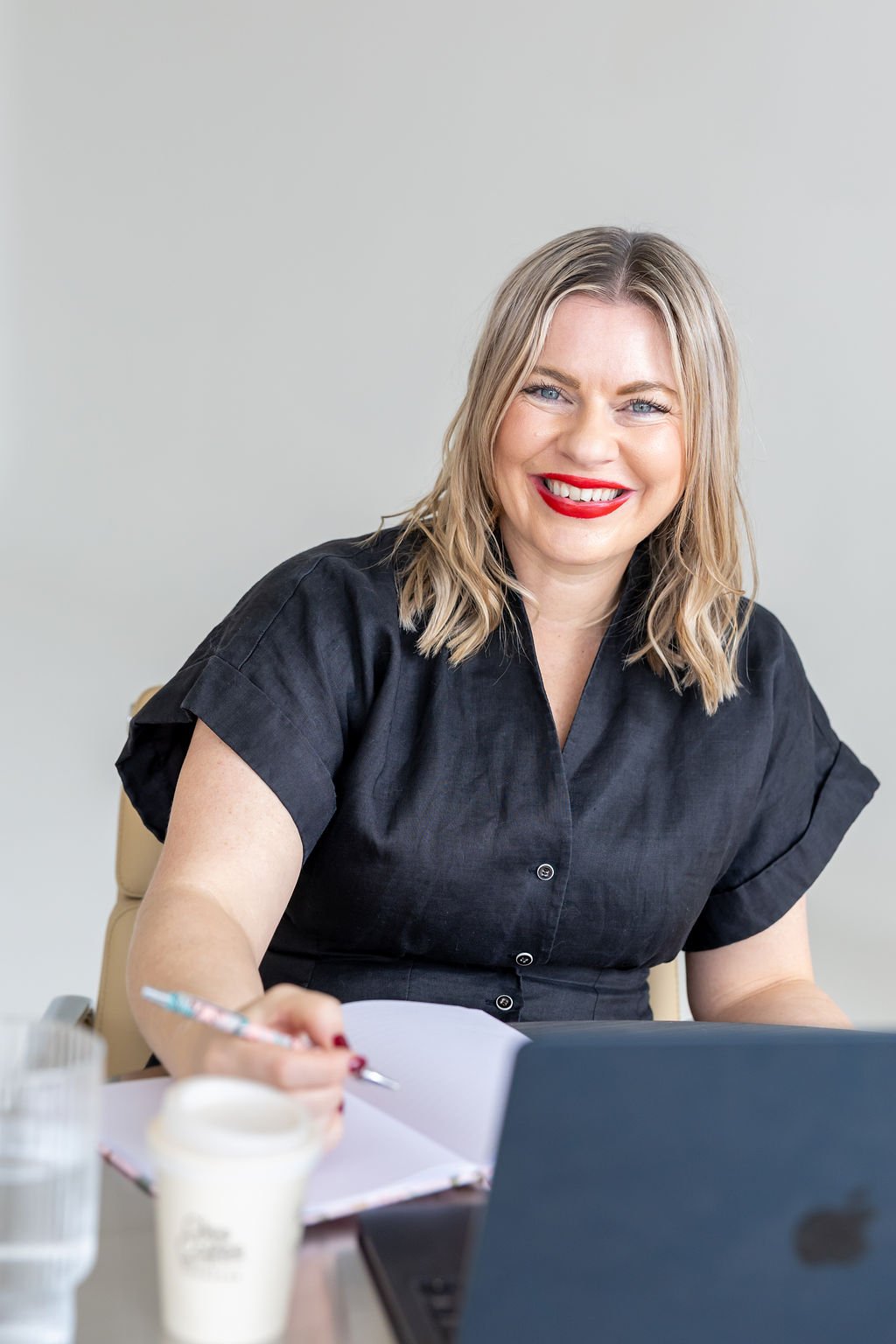 Portrait of Bec Sands, seated at her desk, writing in a notebook