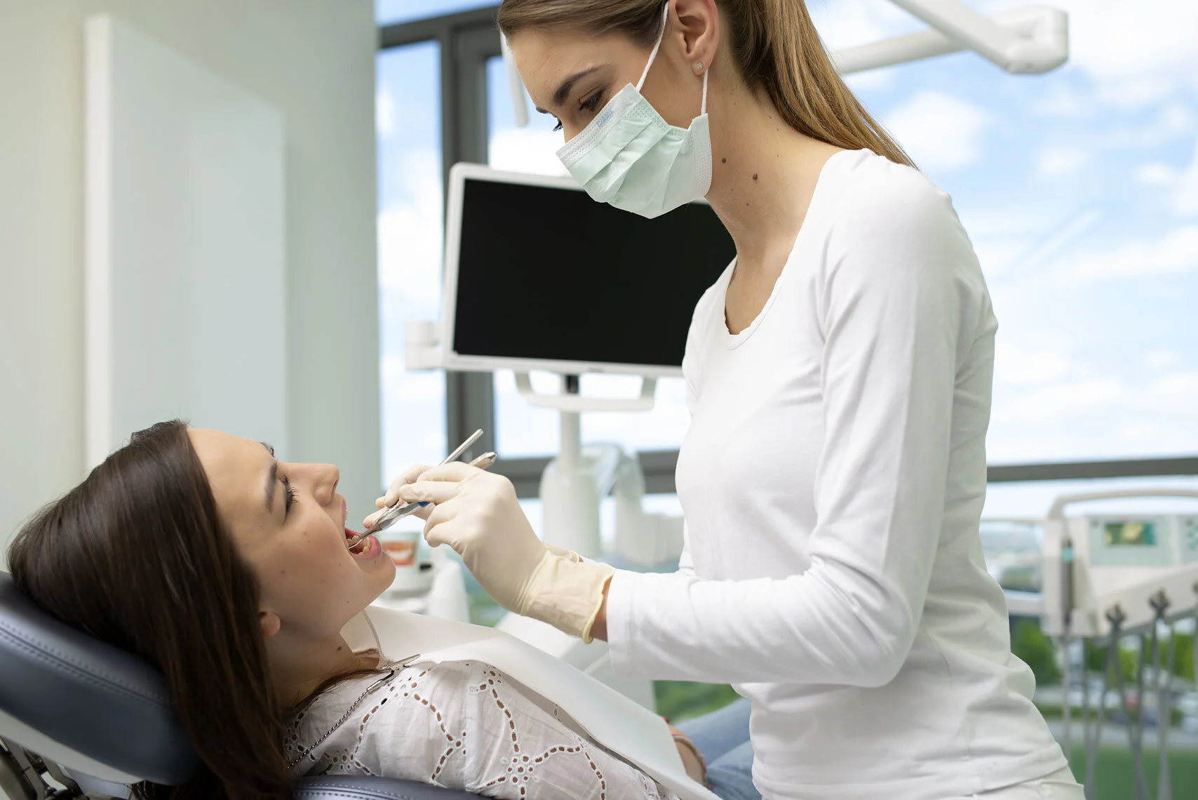 Zahnärztin kontrolliert eine Patientin im Zahnarztstuhl