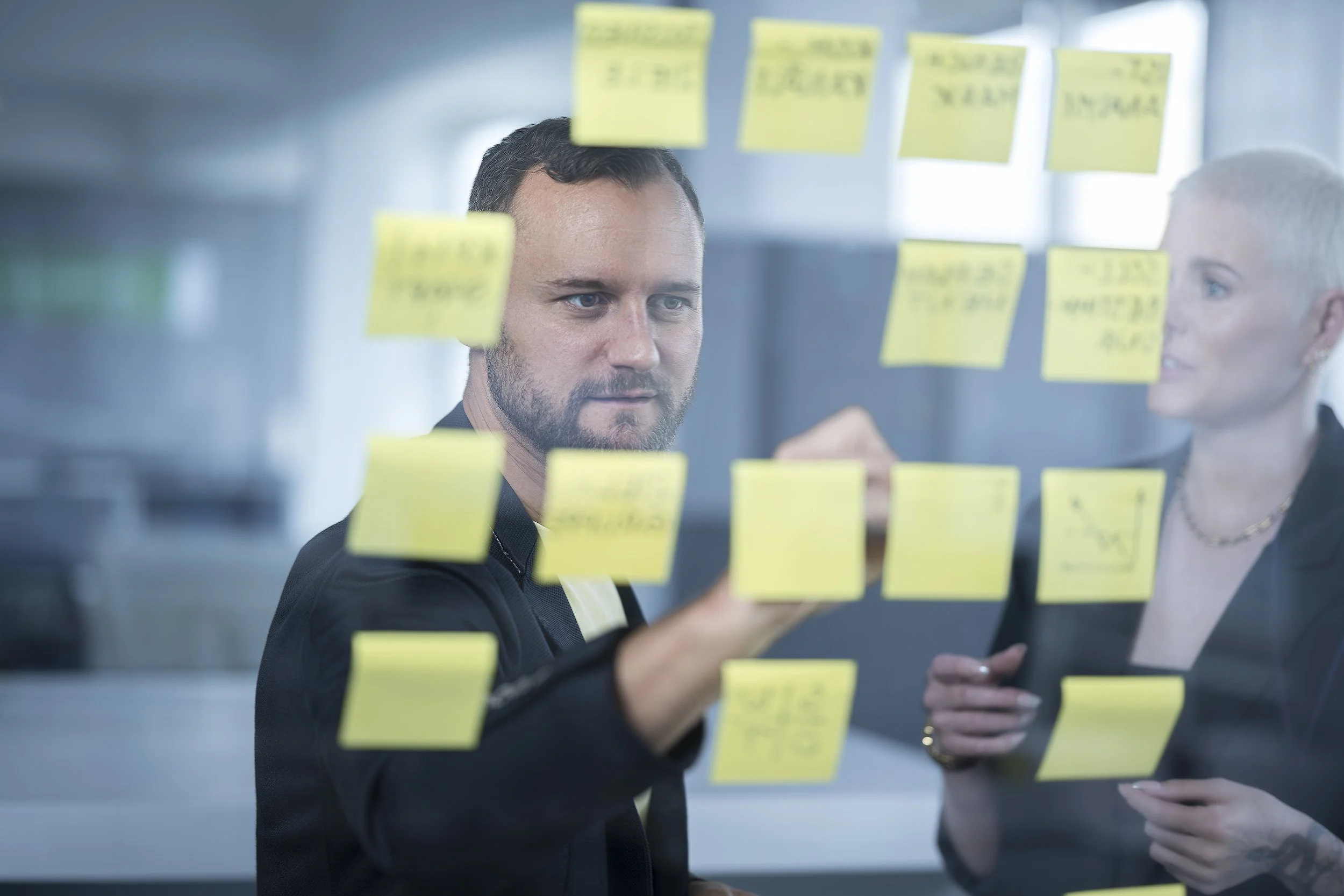 Sticky notes werden von Mitarbeiter an Pinwand geklebt