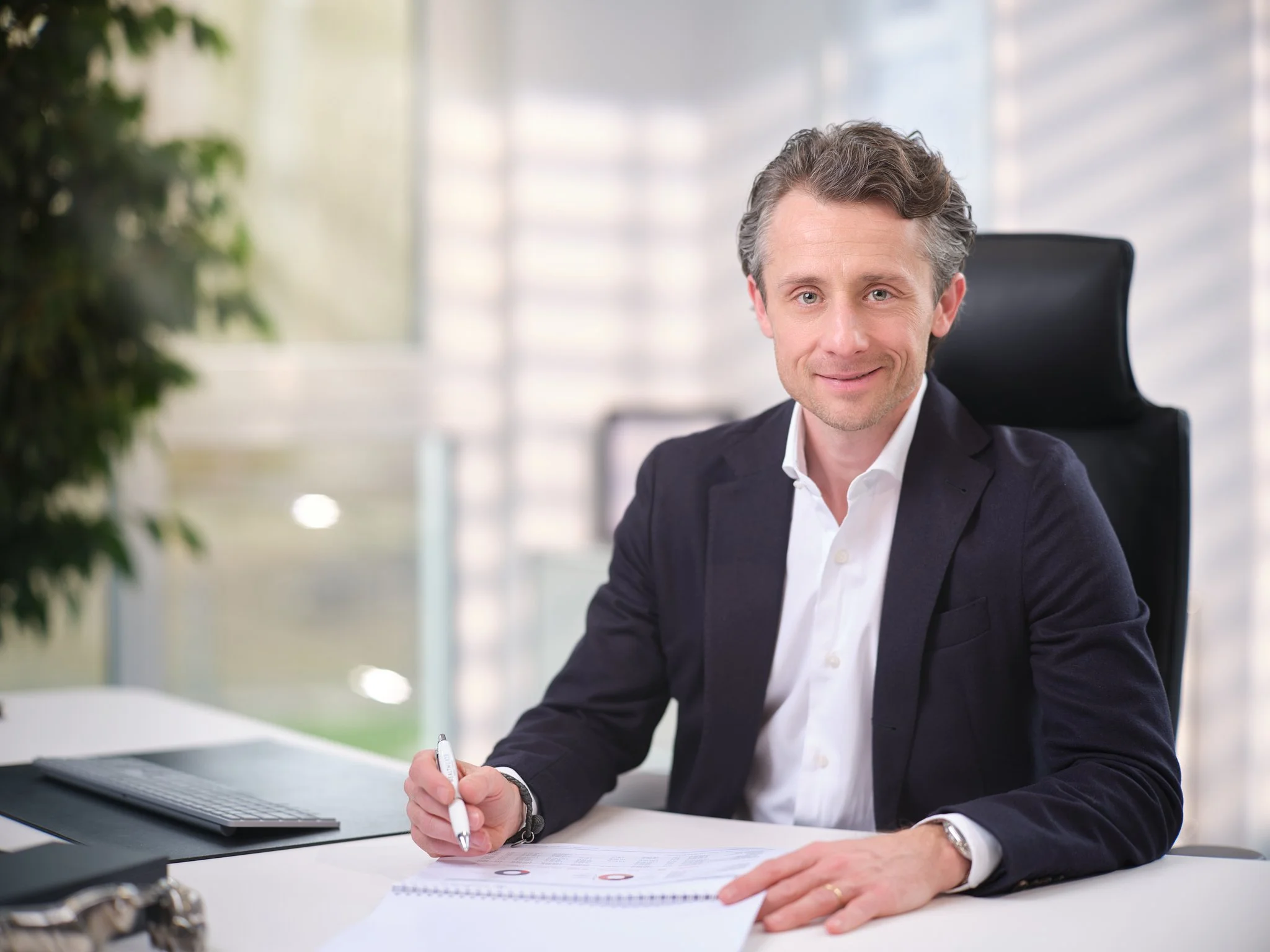 CEO sitzt in Büro und schaut in Kamera