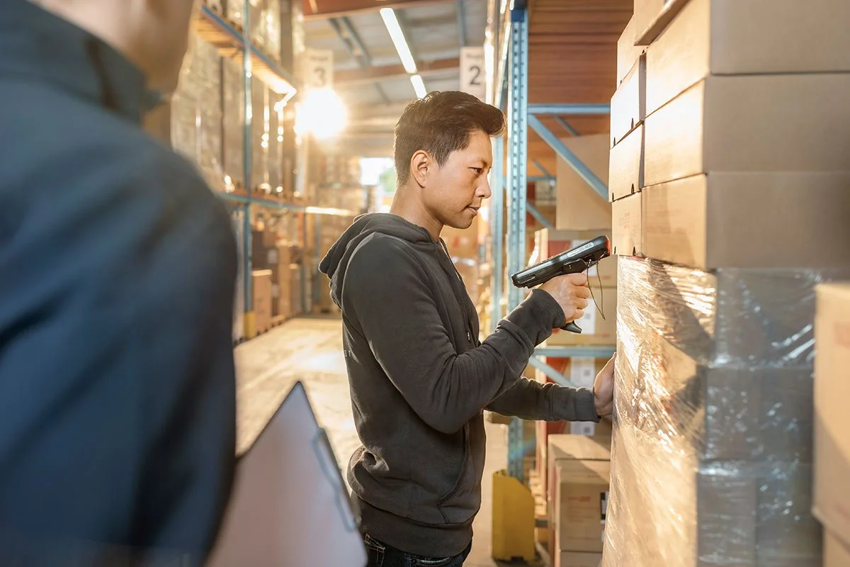 Mann im Lager bei der Inventur mit Barcode-Scanner