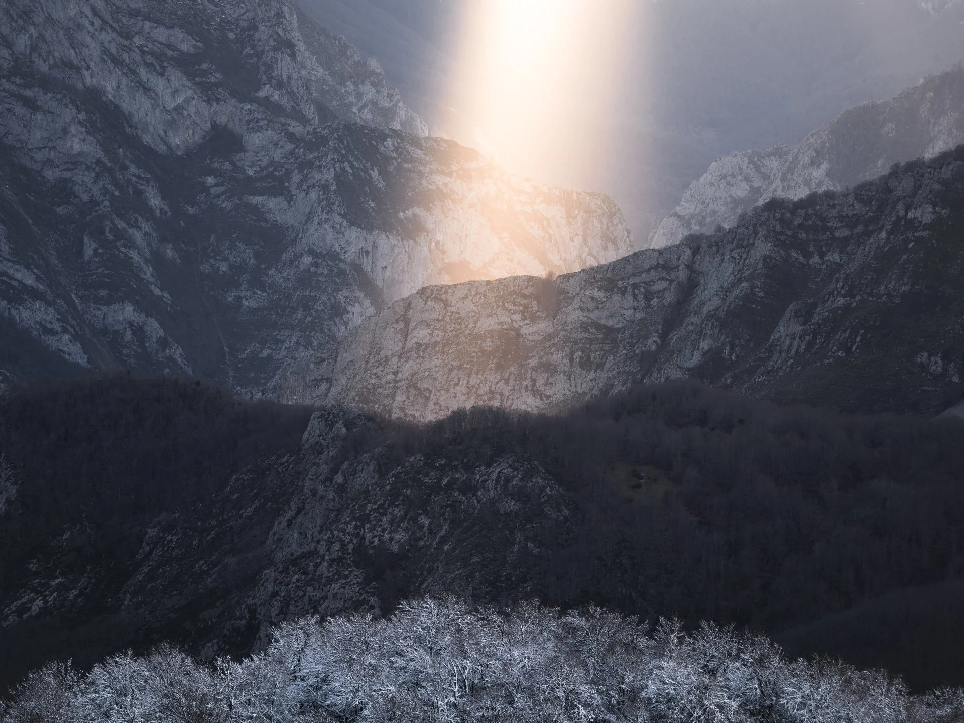 Fotografia de Paisagem nos Picos da Europa. Montanhas cobertas de neve sob céu parcialmente nublado ao pôr do sol