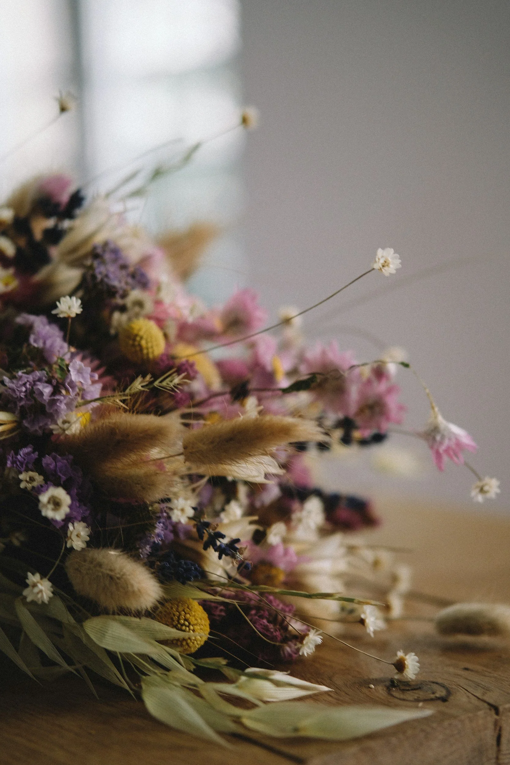 A close-up of a bouquet of dried wildflowers on a wooden surface.