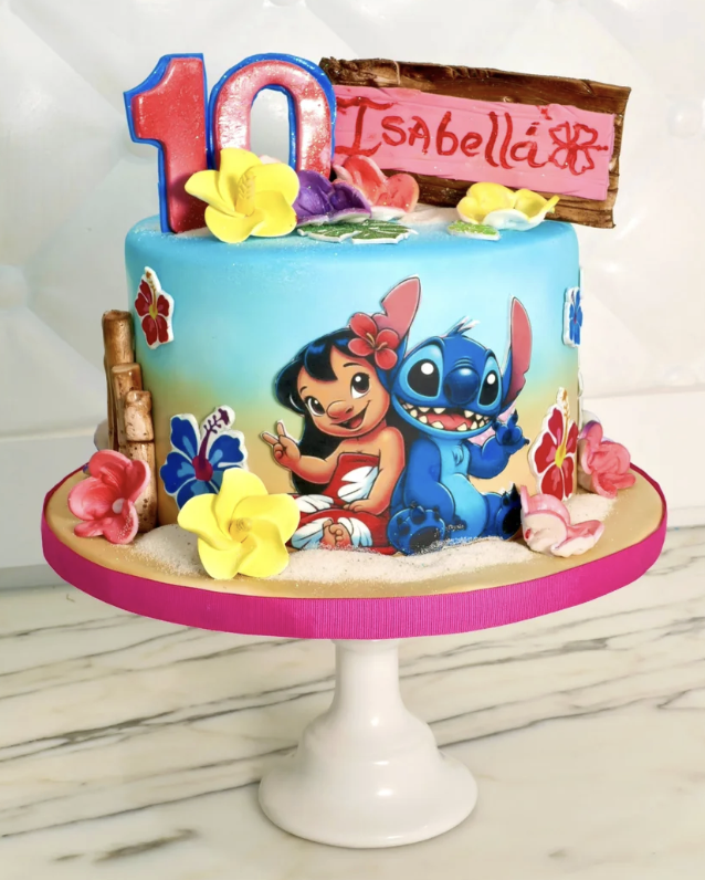 Colorful birthday cake with Disney Lilo & Stitch theme, decorated with flowers, a large red and blue number 10 candle, and an edible sign that reads 'Isabella'.