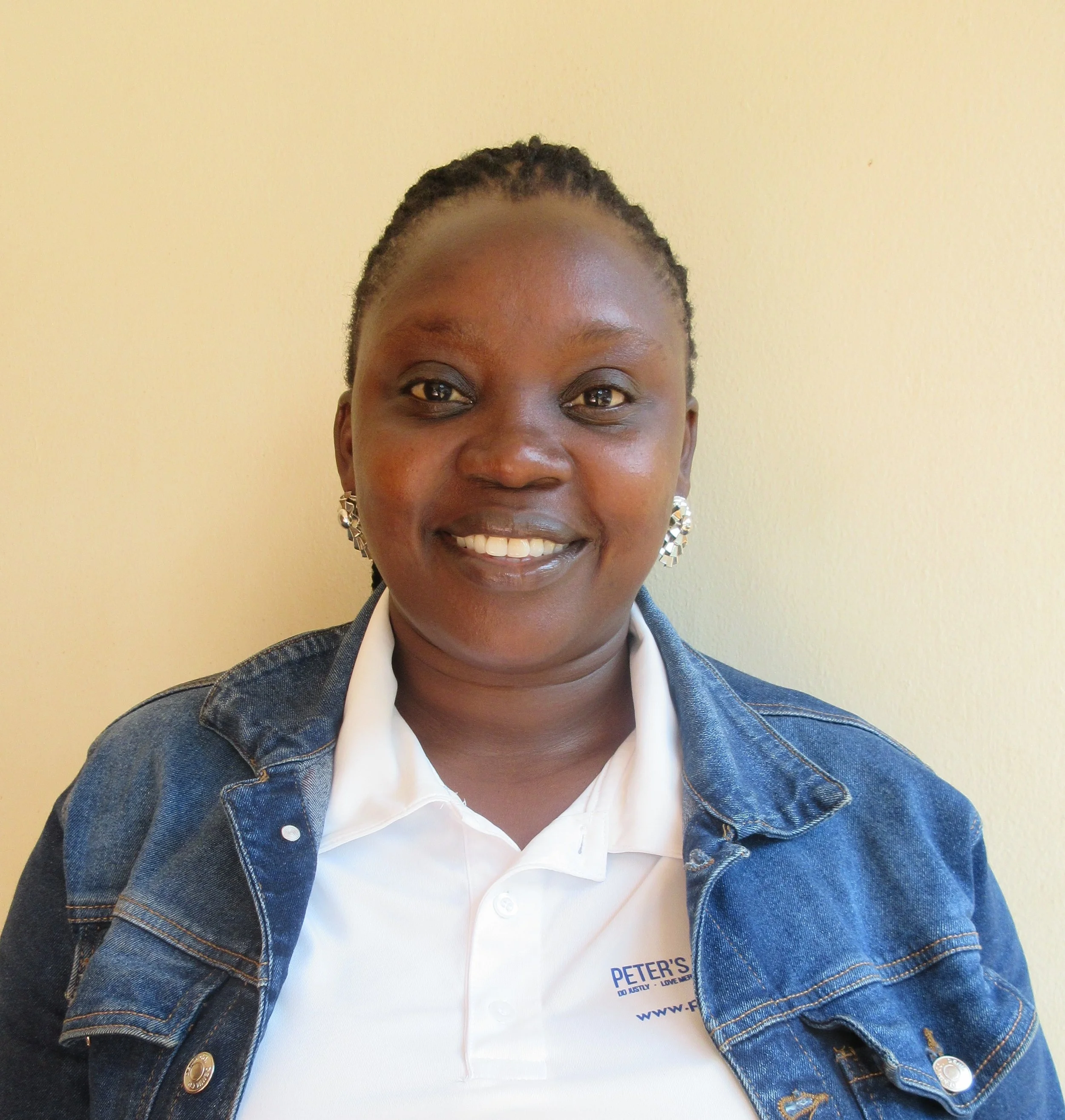 Portrait of a woman with dark skin, wearing white shirt and denim jacket.